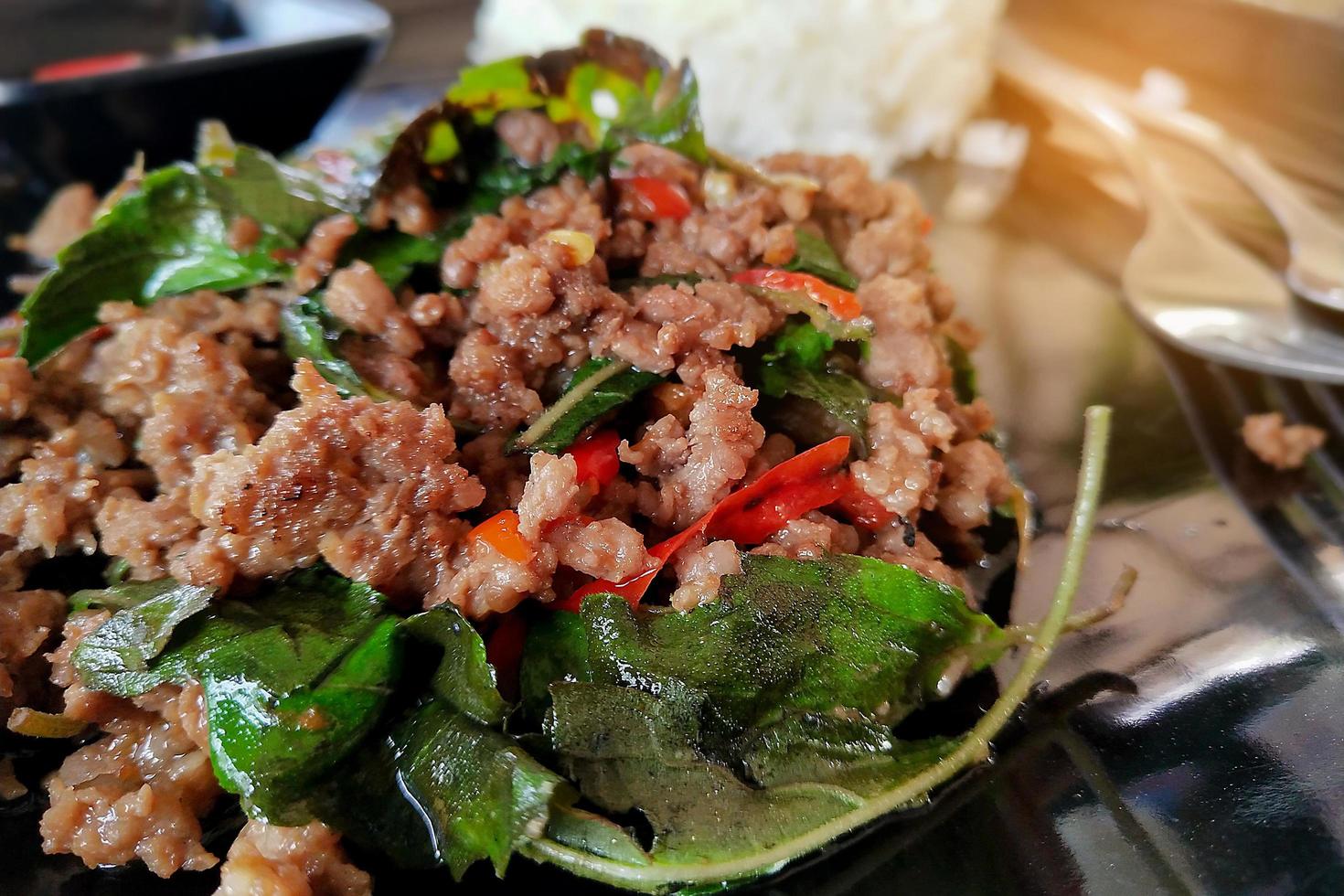 mescolare la carne tritata fritta con peperoncino e basilico e riso al vapore sulla piastra nera foto