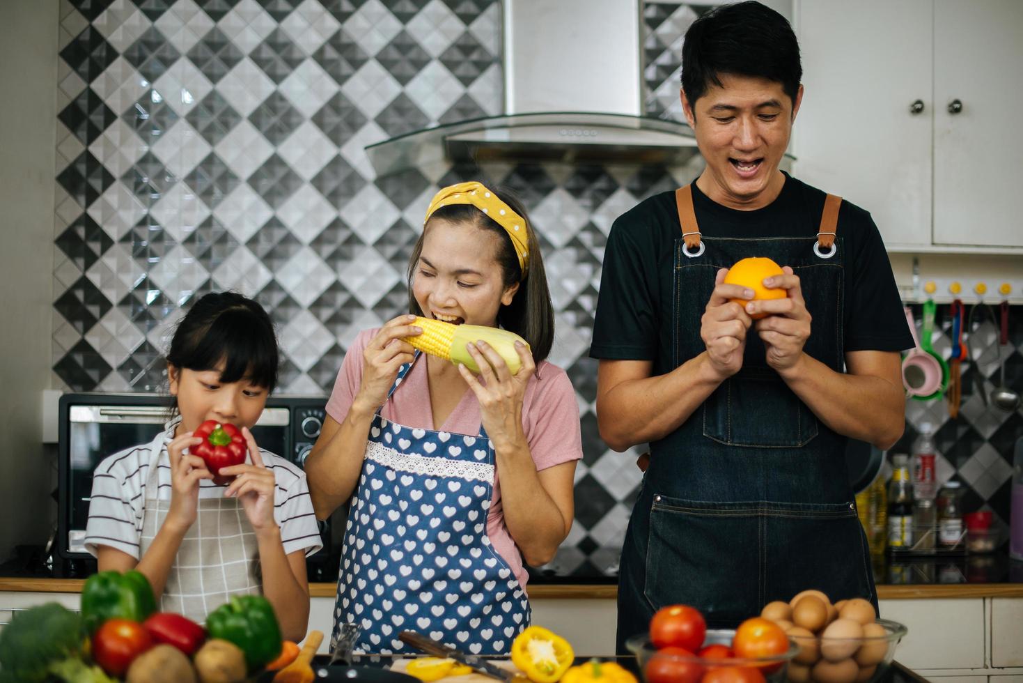famiglia felice tagliare le verdure insieme nella loro cucina foto