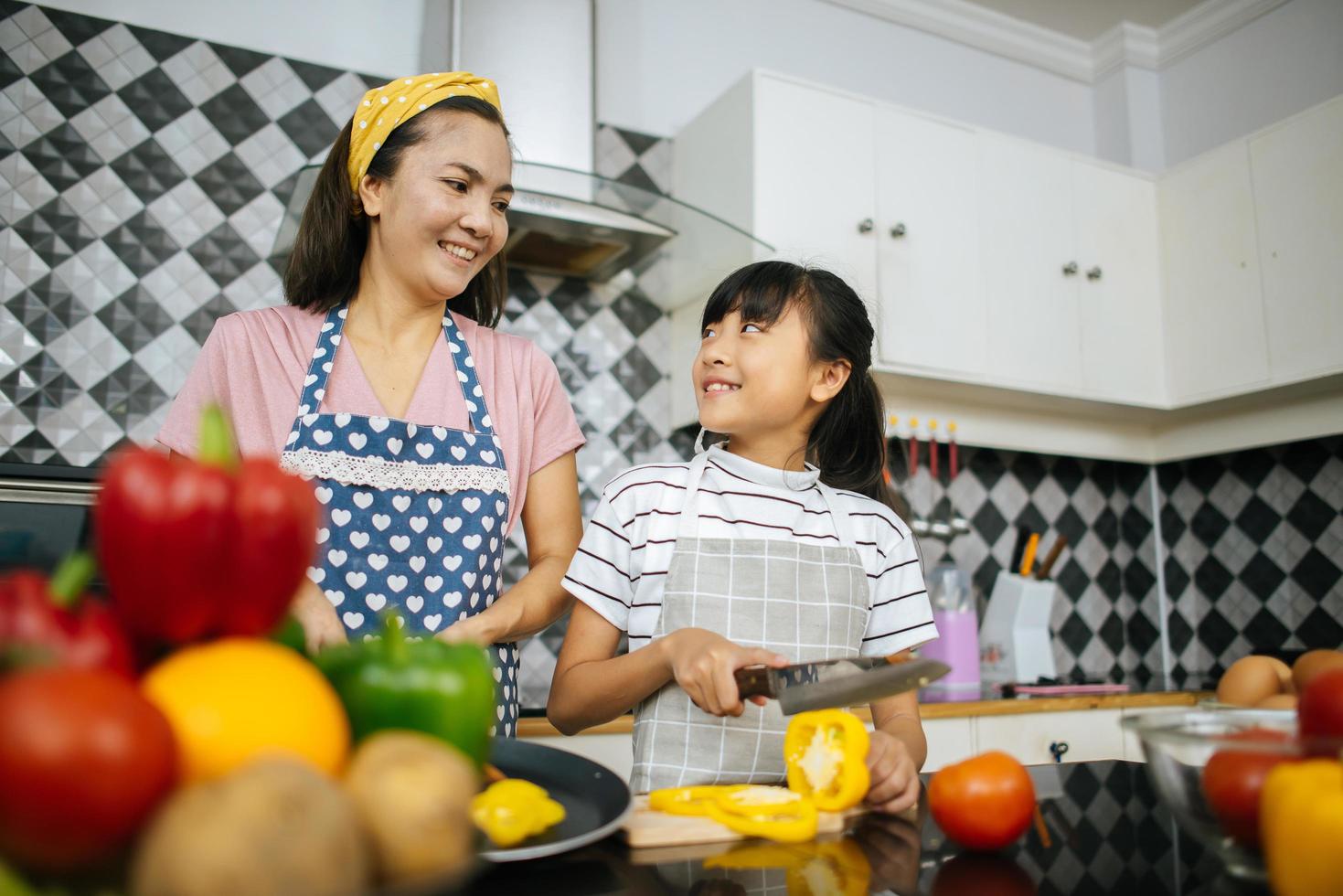 mamma e sua figlia si aiutano a vicenda nella loro cucina di casa foto