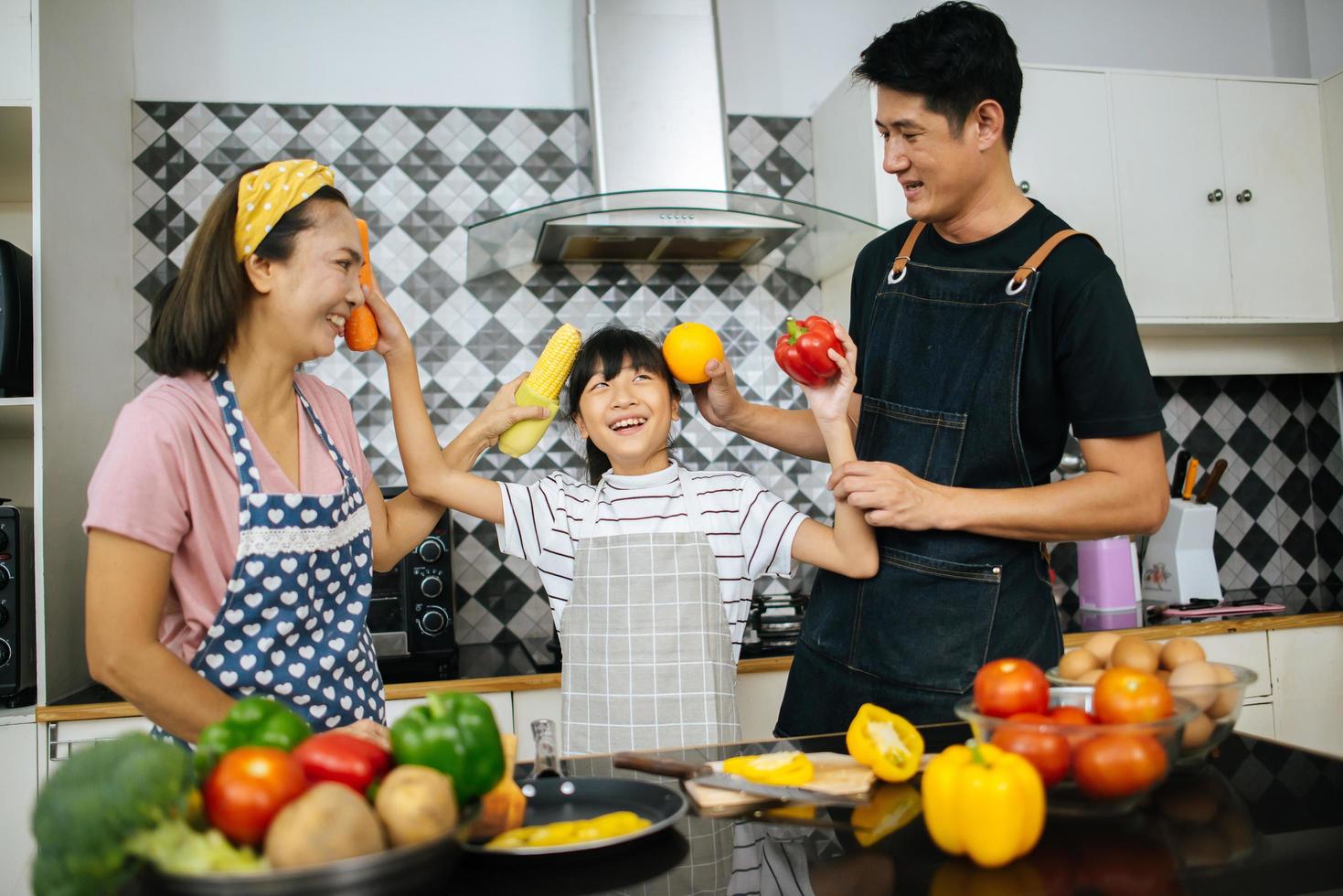 famiglia felice tagliare le verdure insieme nella loro cucina foto