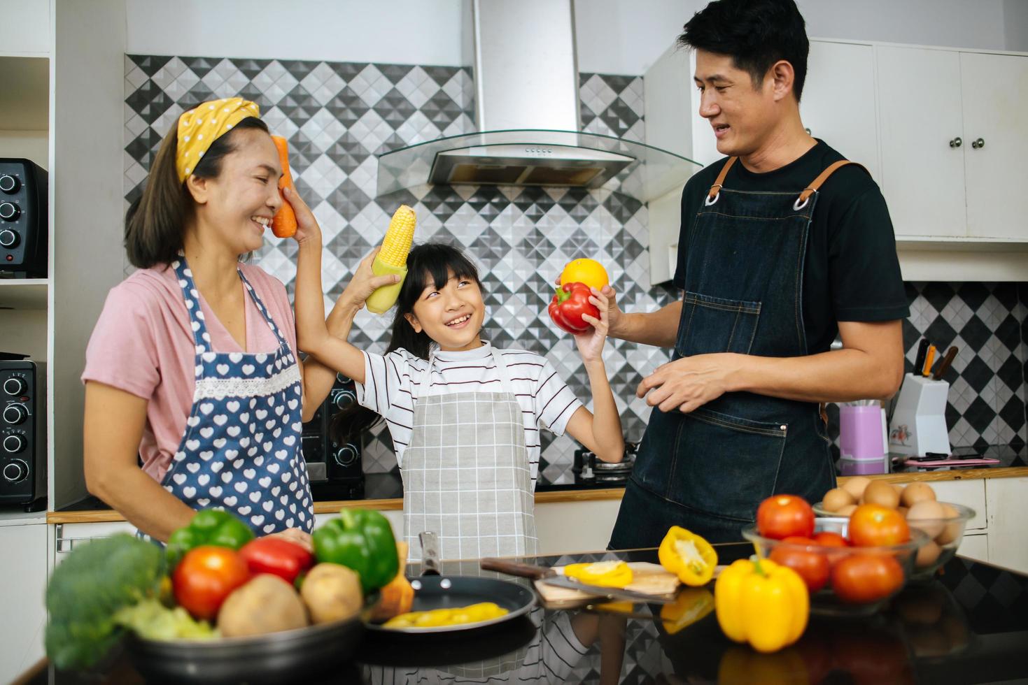 famiglia felice tagliare le verdure insieme nella loro cucina foto