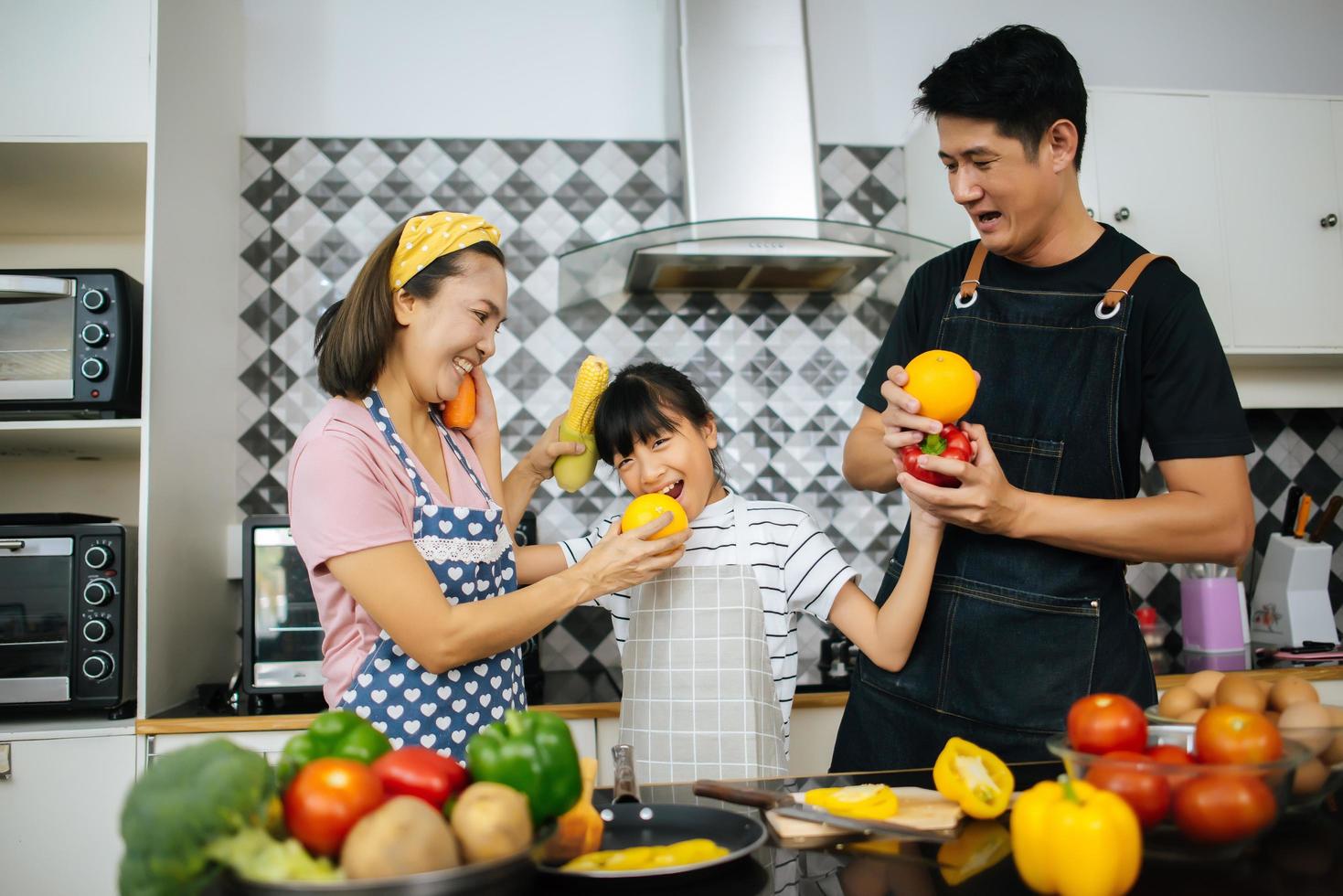 famiglia felice tagliare le verdure insieme nella loro cucina foto