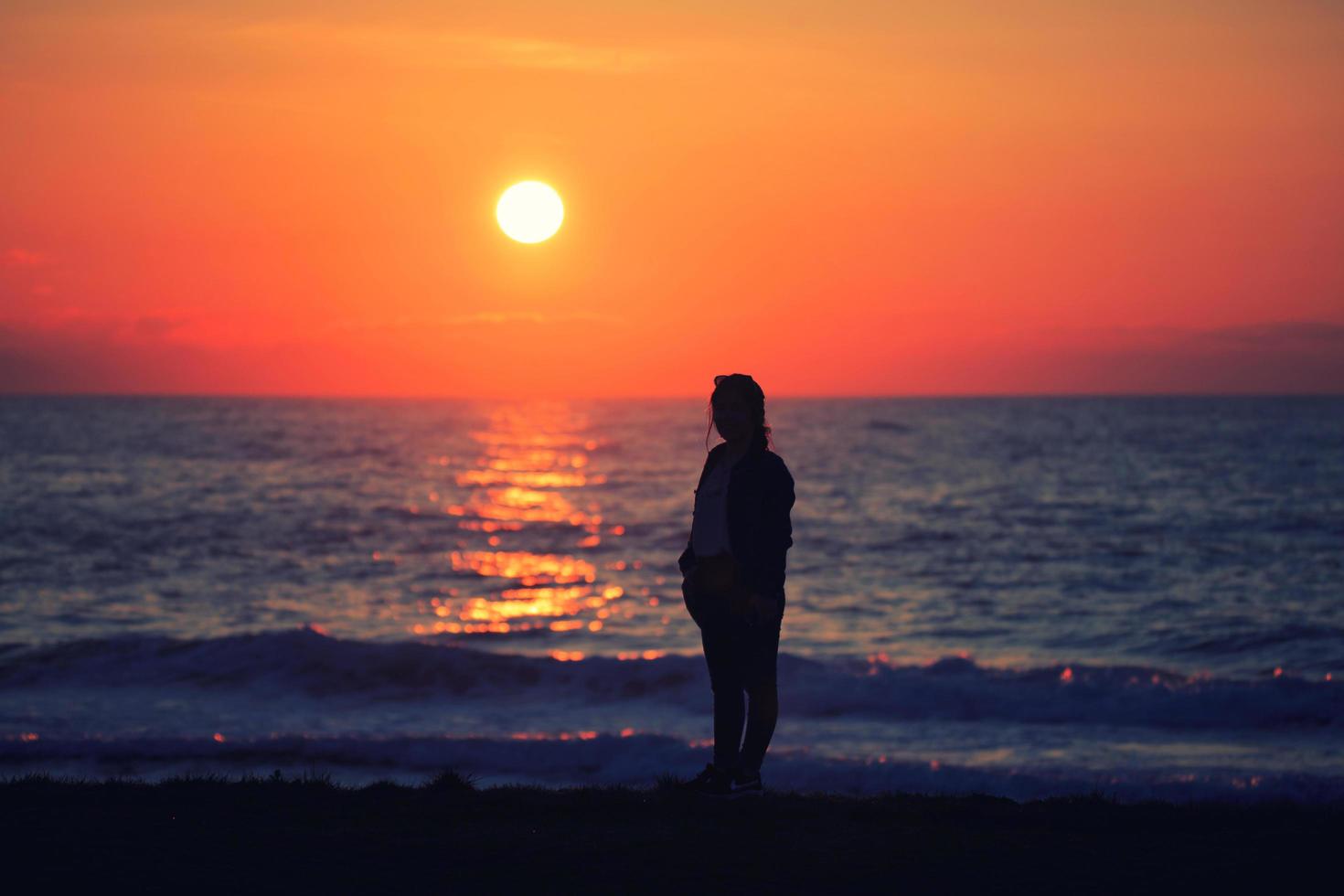 una donna fotografa guardando il tramonto foto