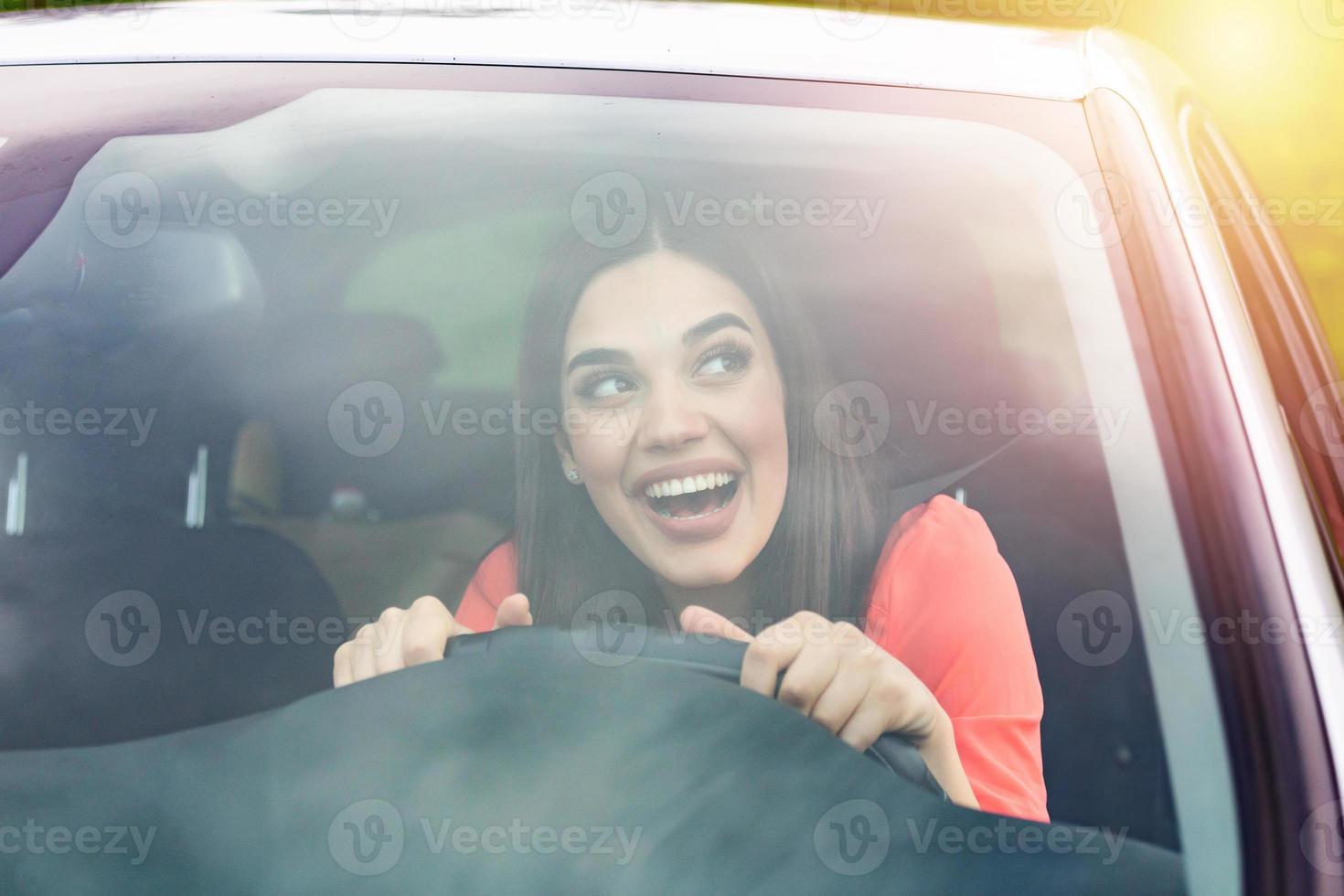 contento brunetta donna guida un' macchina. ritratto di bellissimo caucasico donna con trentadue denti Sorridi e Marrone capelli guida macchina. mano su timone ruota. giovane donna guida un' auto nel il città foto