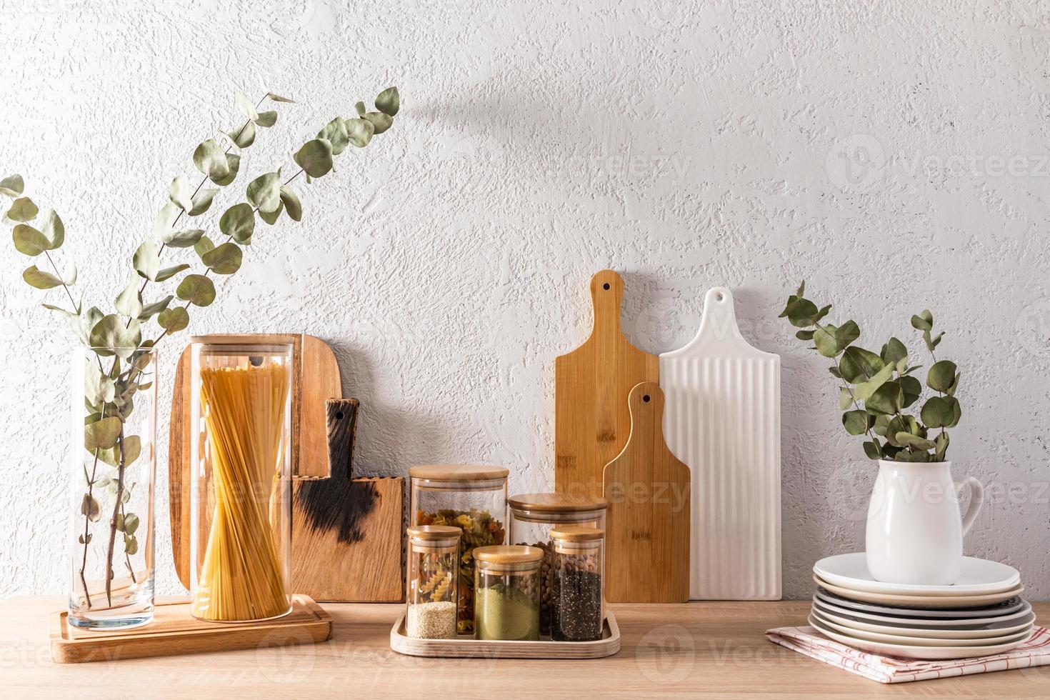 elegante cucina sfondo nel leggero colori con bicchiere barattoli per massa prodotti, decorativo elementi contro il sfondo di un' grigio strutturato parete. foto