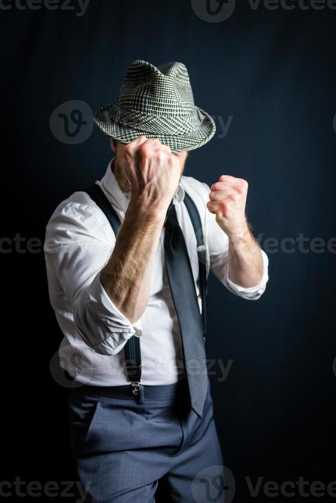 ritratto di uomo d'affari nel bianca vestito camicia e vecchio fedora cappello con pugni sollevato pronto per combattere. Vintage ▾ stile e retrò moda di film noir investigatore o crimine combattente. foto