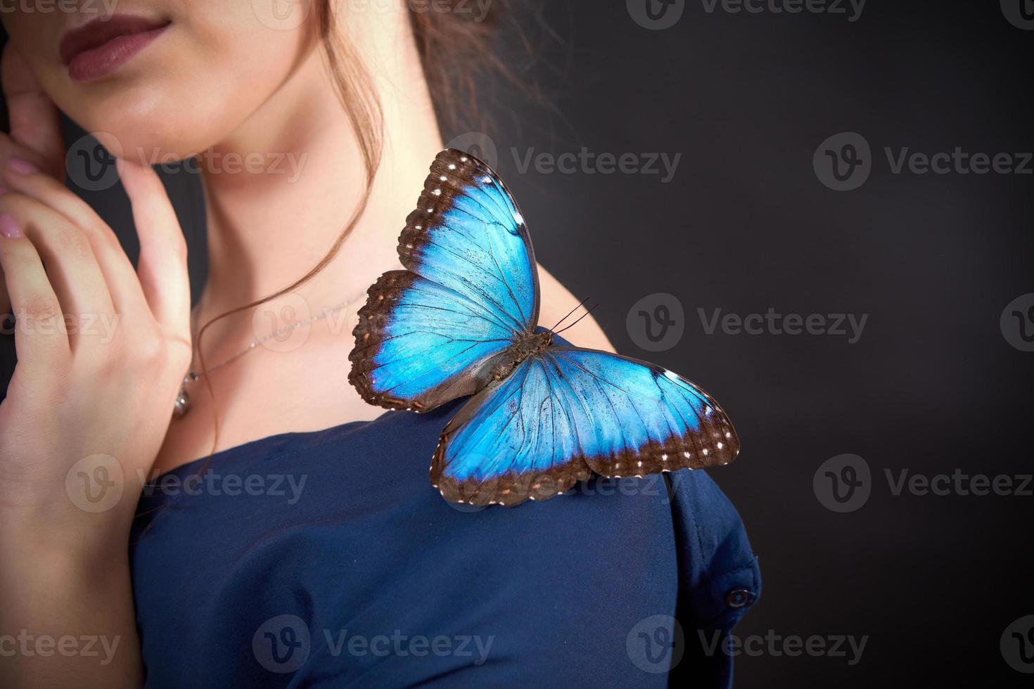 avvicinamento di un' blu farfalla su un' giovane ragazze spalla su un' buio sfondo. il concetto fragilità di natura foto