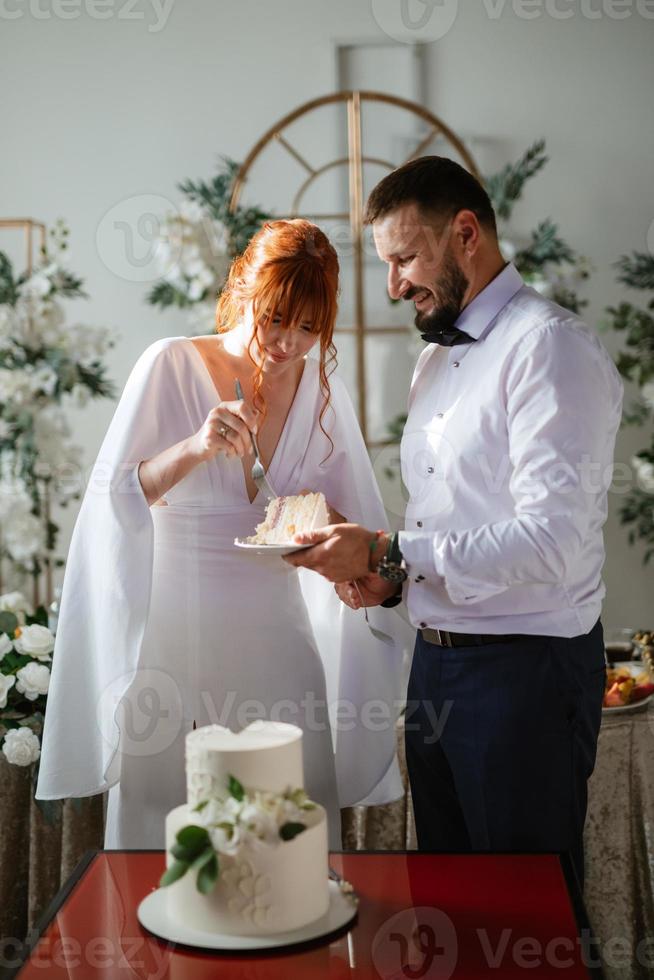 Novelli sposi felicemente tagliare e gusto il nozze torta foto