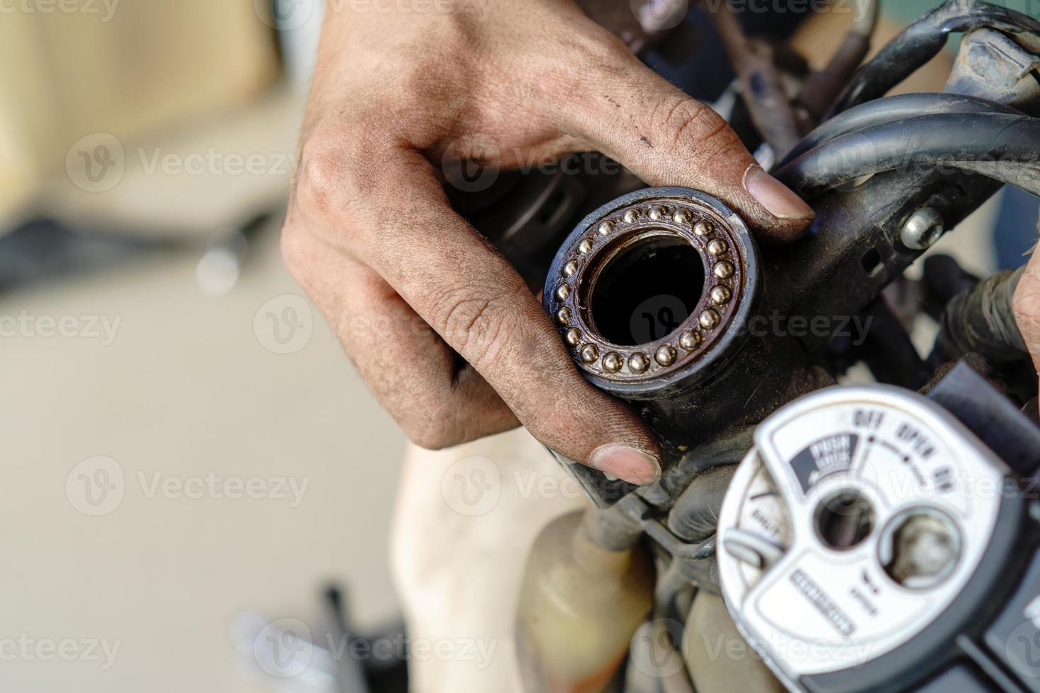 meccanico ispezionare e regolare motociclo timone testa cuscinetti, Manutenzione, riparazione motociclo concetto nel box auto .selettivo messa a fuoco foto