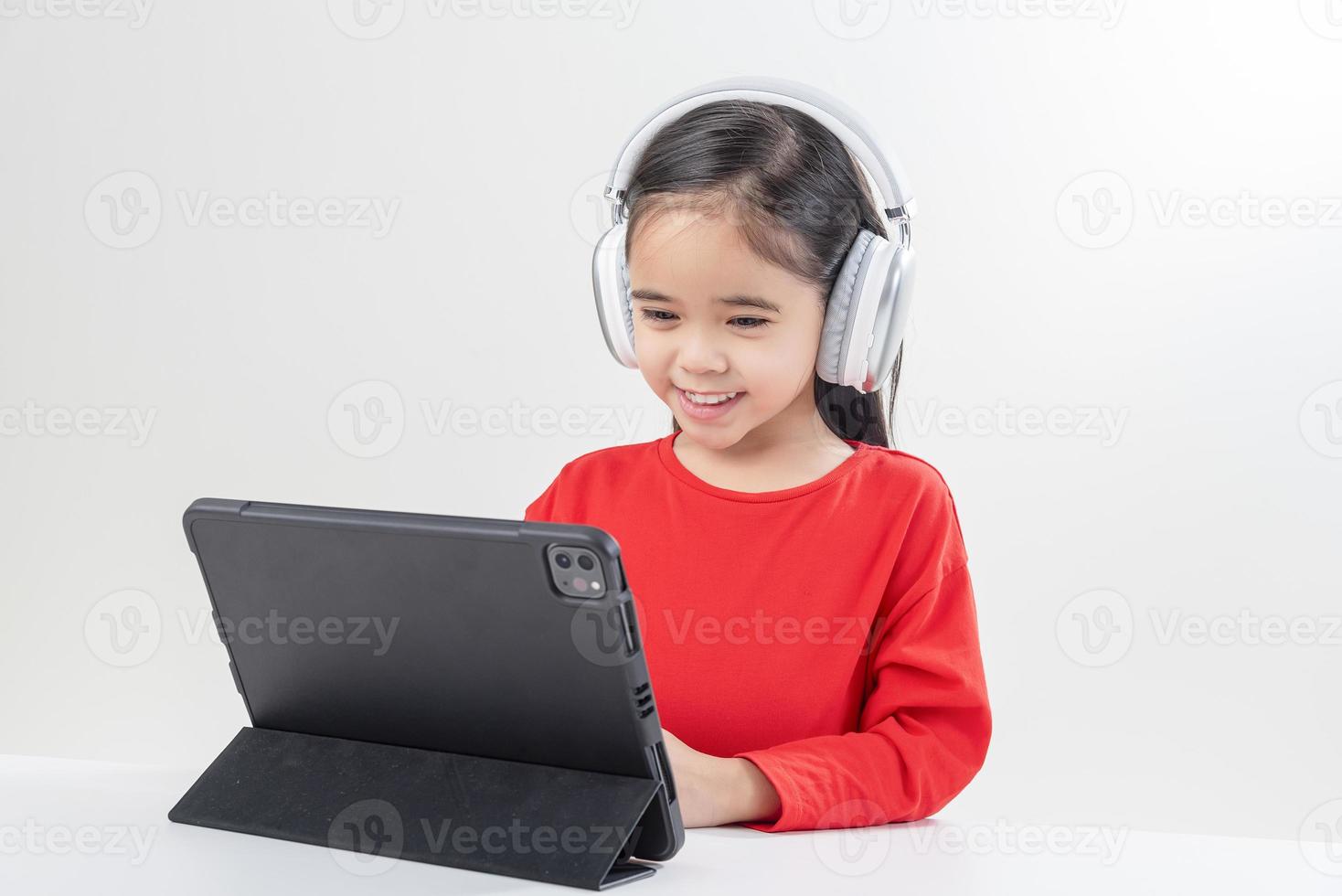 poco ragazza Asia carino mettere su cuffie avere video chiamata lontano classe con insegnante utilizzando computer portatile, studia in linea su computer, homeschooling concetto foto