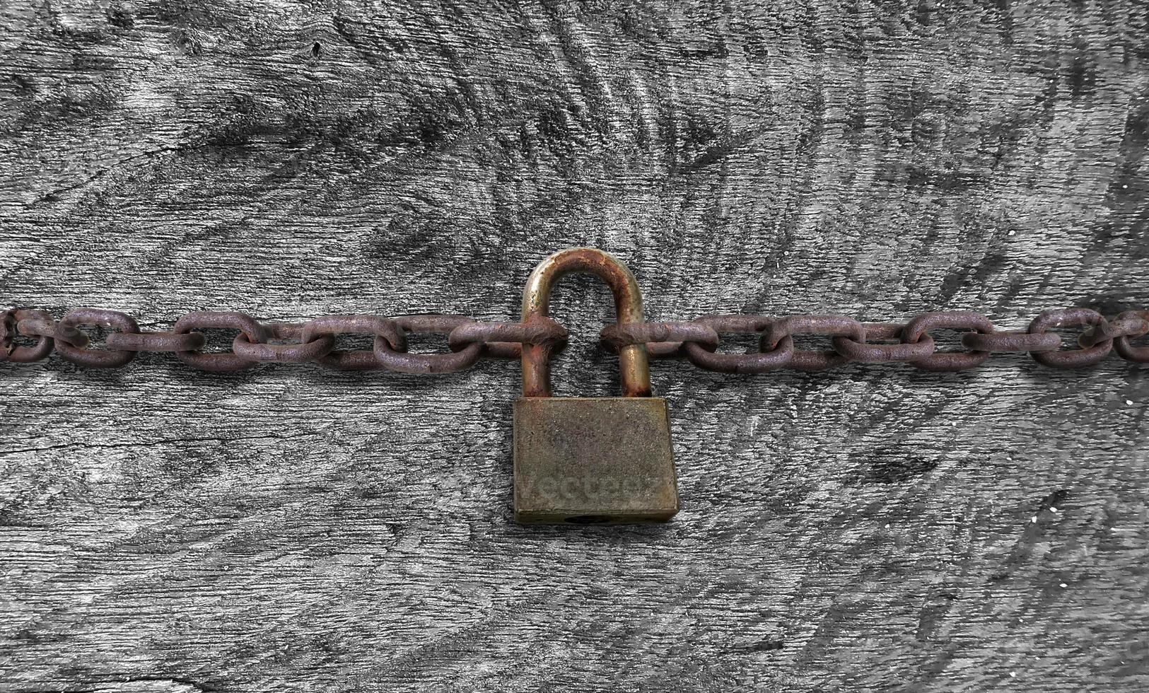 un vecchio arrugginito lucchetto chiuso su un' massiccio catena su Vintage ▾ di legno tavolo foto