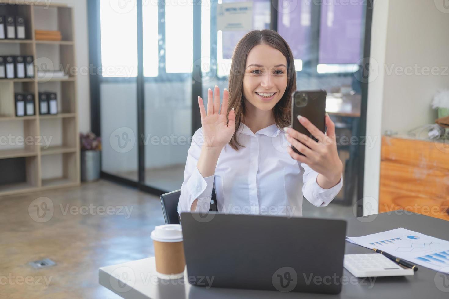 marketing, finanza, contabilità, pianificazione. caucasico donna d'affari Tenere mobile Telefono e mostrando buona volontà nel cliente unendo attività commerciale con azienda per aumentare profitto di il computer portatile ufficio e documenti foto