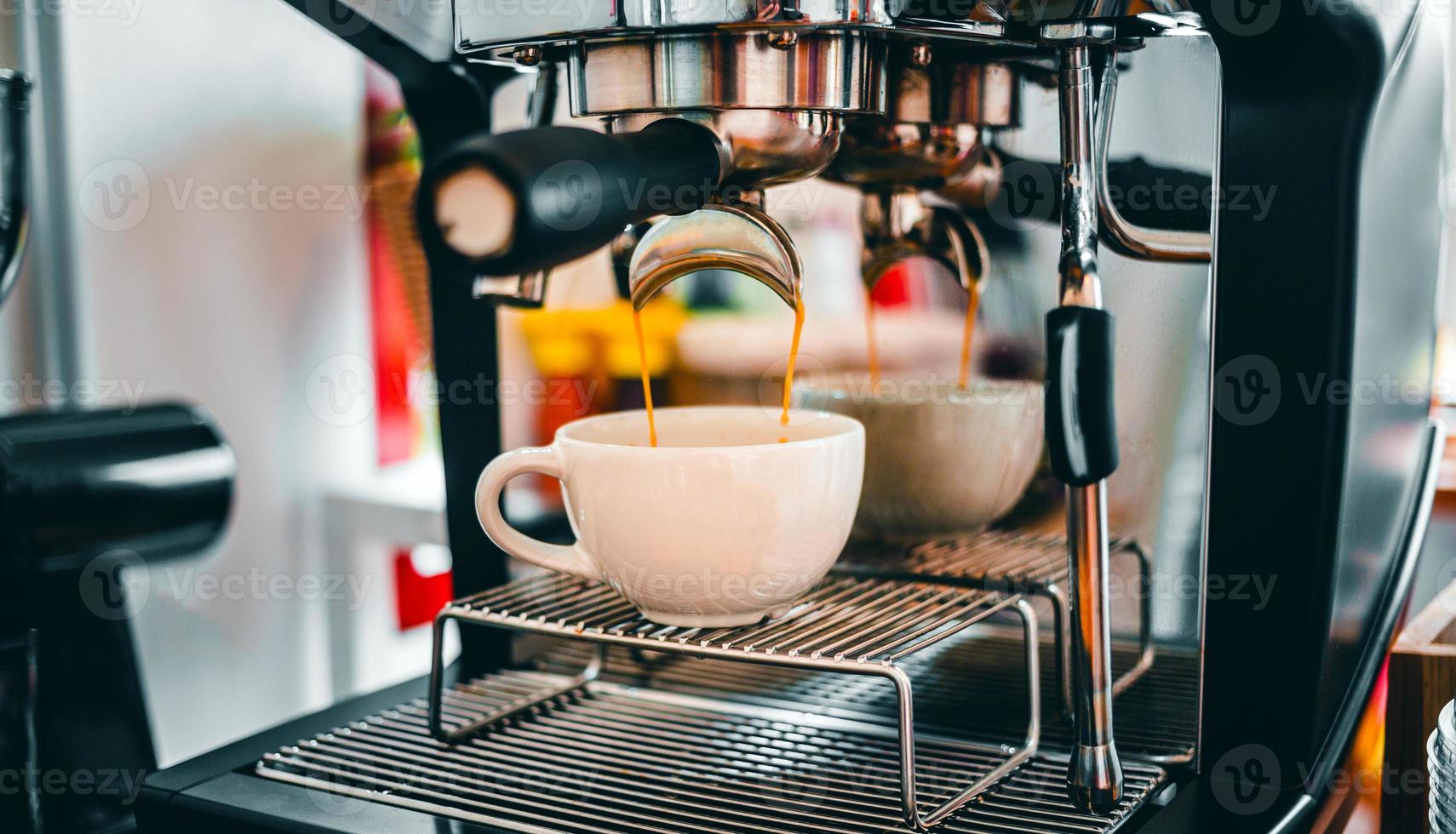 caffè estrazione a partire dal il caffè macchina con un' portafilter scrosciante caffè in un' tazza, espresso poro a partire dal caffè macchina a caffè negozio foto