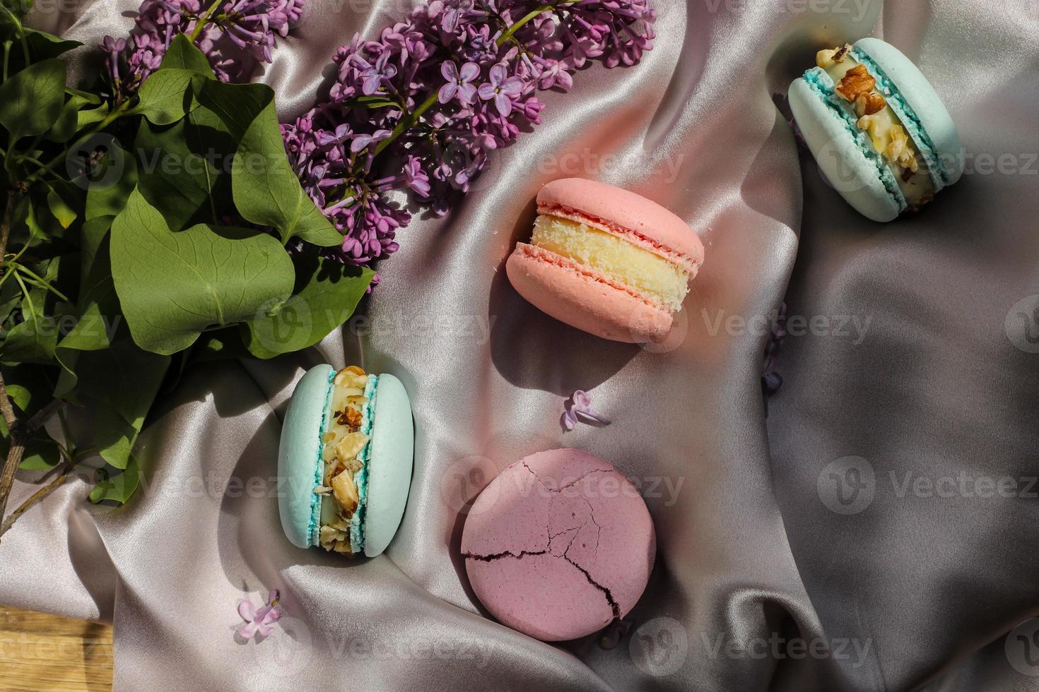 amaretti francesi rosa e menta o biscotti macarons e fiori lilla su uno sfondo di stoffa. aromi naturali di frutta e bacche, ripieno cremoso per san valentino festa della mamma pasqua con cibo d'amore foto