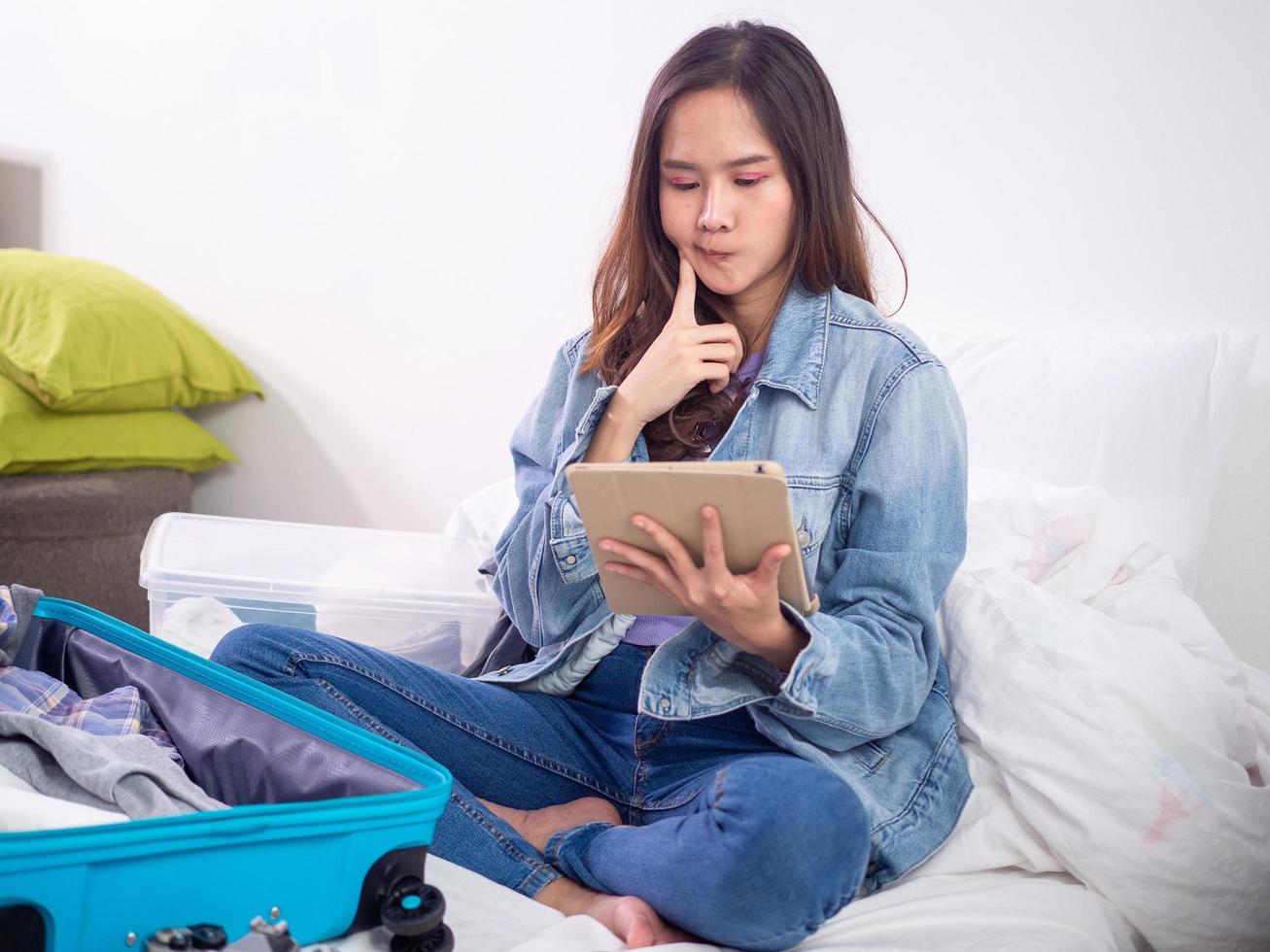 asiatico donne confezionato bagaglio per il imminente estate vacanze. donne siamo guardare per un' sicuro posto. elementi necessario per viaggio durante il scoppio di covid19. backpackers e viaggio concetti. foto