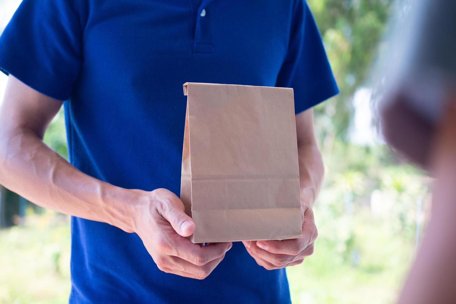 il fattorino trasporta un' cibo Borsa e indossa un' maschera, pronto per consegnare cibo in linea come per il clienti ordine per Presto casa consegna e gratuito spedizione. in linea shopping e esprimere consegna foto