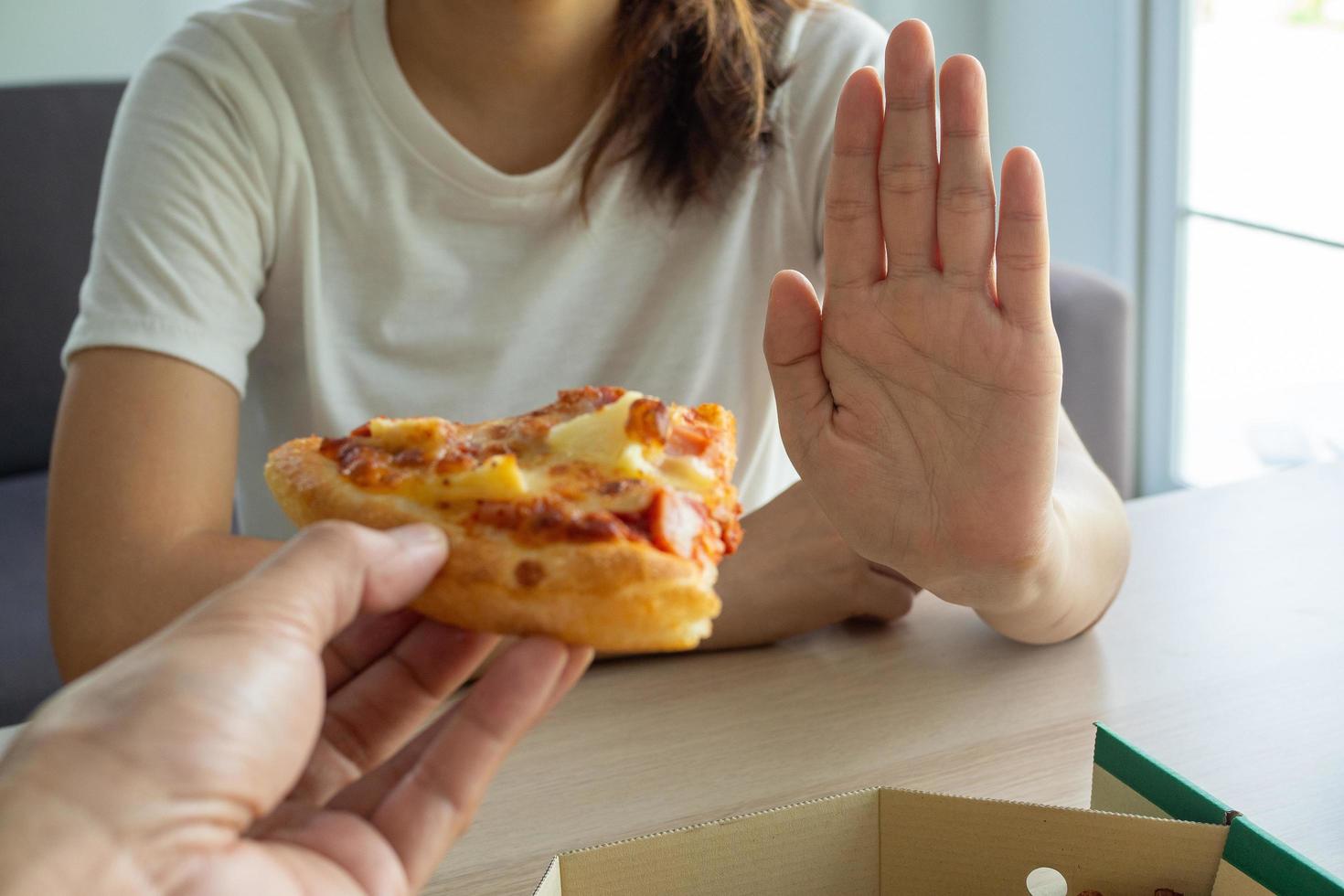 il donna prende cura Salute e peso rifiuto un' pezzo di Pizza quello sua amico spedito. bene Salute e peso controllo. dieta concetto foto