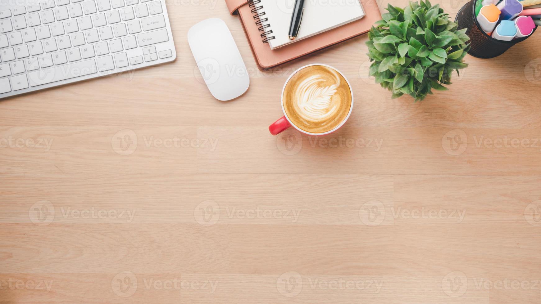 ufficio di legno scrivania posto di lavoro con tastiera del computer, topo, taccuino, penna e tazza di caffè, superiore Visualizza piatto posare con copia spazio. foto