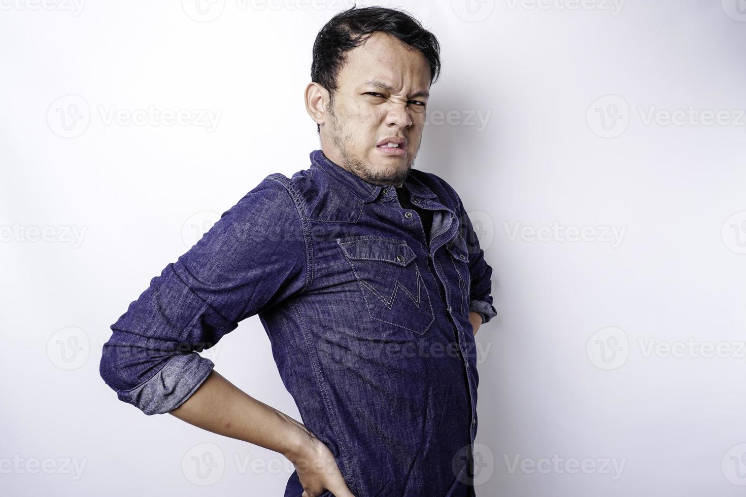 stanco irritato giovane uomo indossa blu camicia sofferenza a partire dal dolore, muscolo spasmo a posto di lavoro. fatica, Scadenza, dolore e scorretto posizione foto