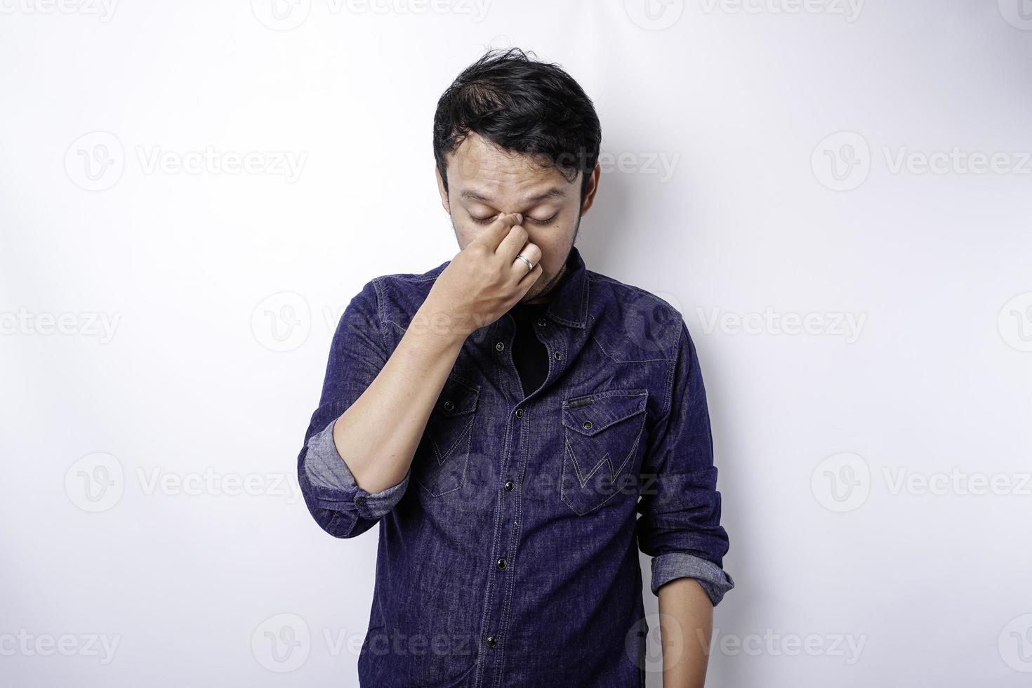 un' ritratto di un asiatico uomo indossare un' blu camicia isolato di bianca sfondo sembra depresso foto
