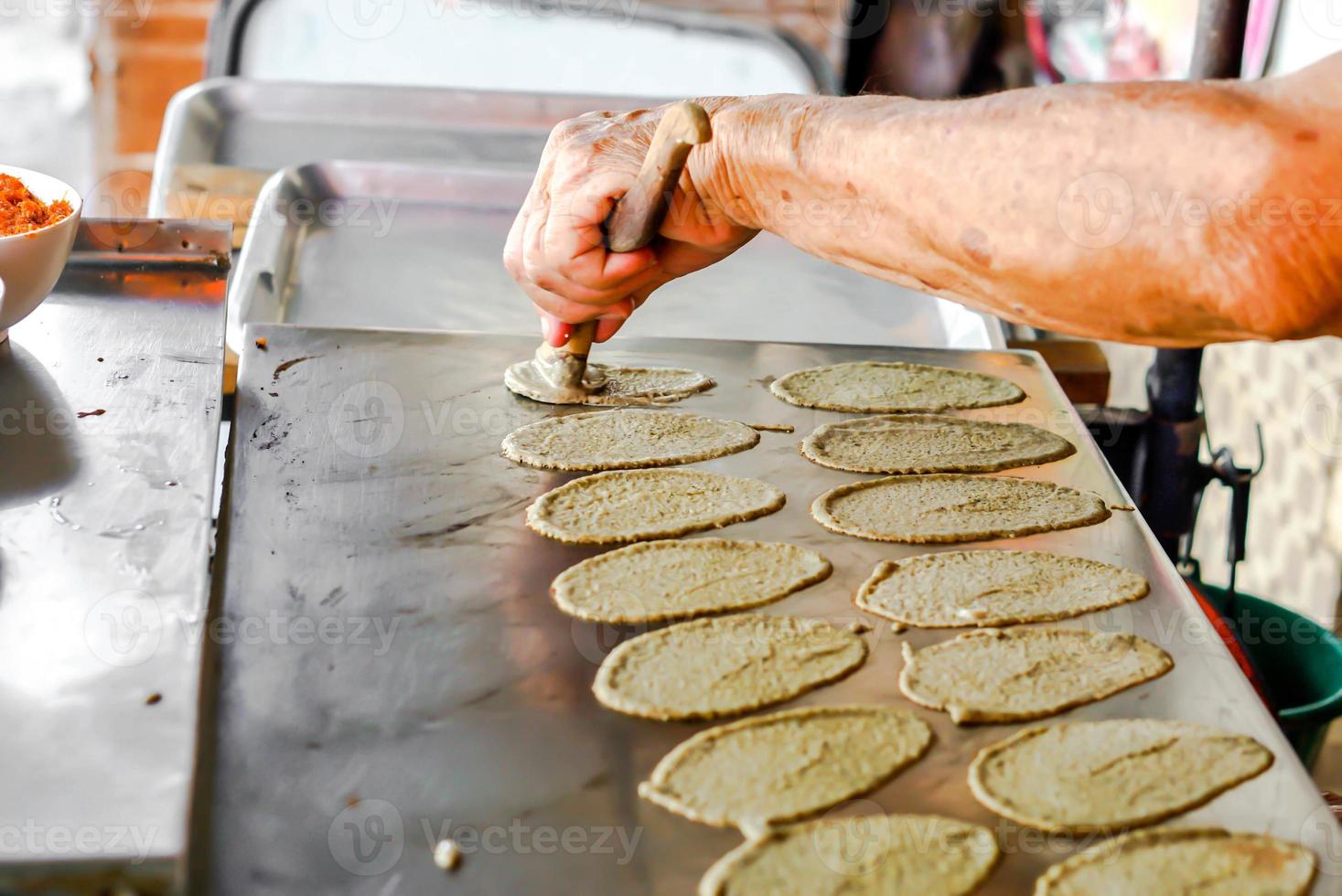 vecchio dell'uomo mano è fabbricazione dolci tailandese croccante pancake per clienti. nel immagine lui mettendo d'oro discussioni dolce su superiore di dolce crema e Impasto fogli. foto