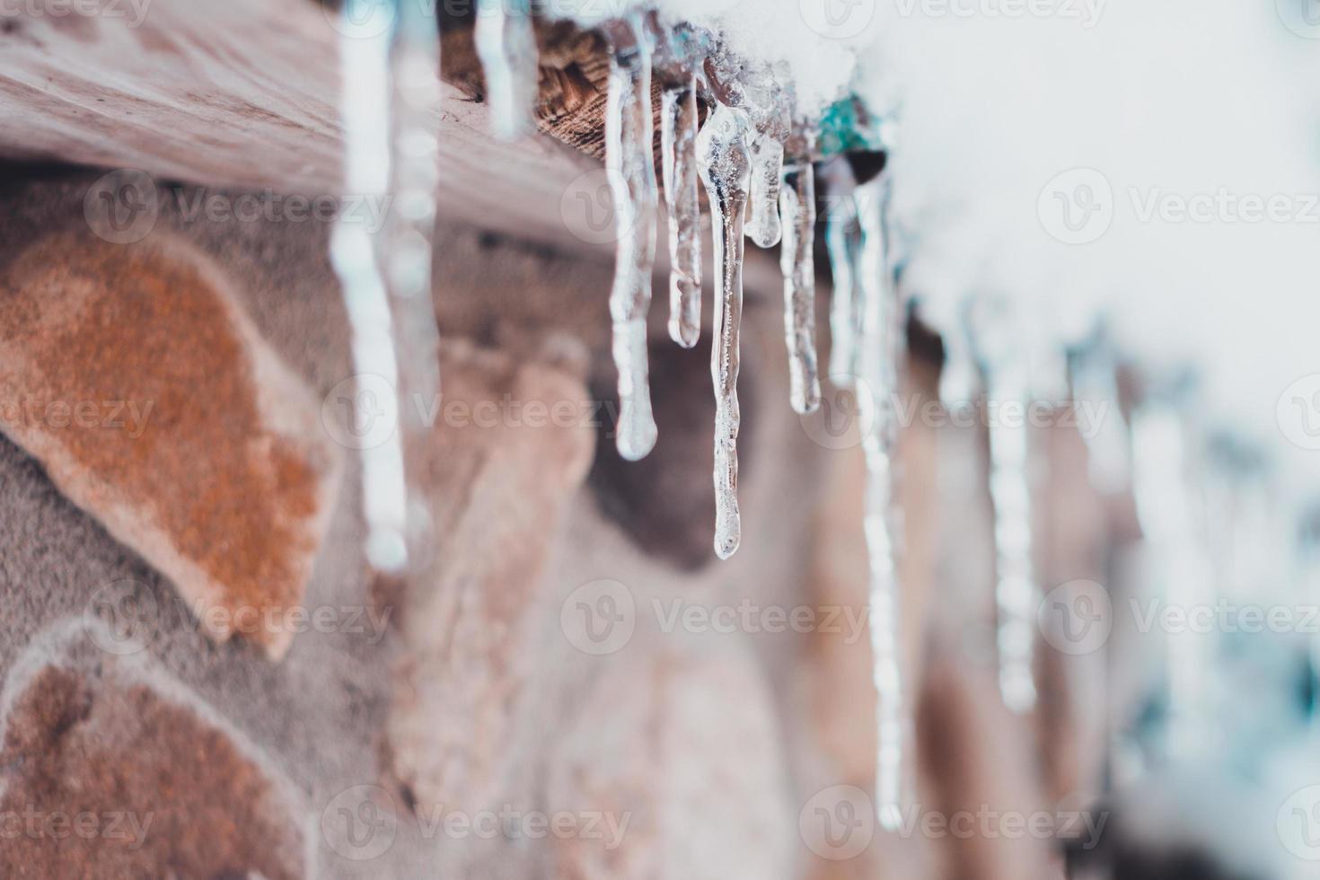 bellissimo ghiacciolo su il tetto di un' Casa nel inverno come il temperatura sorge foto