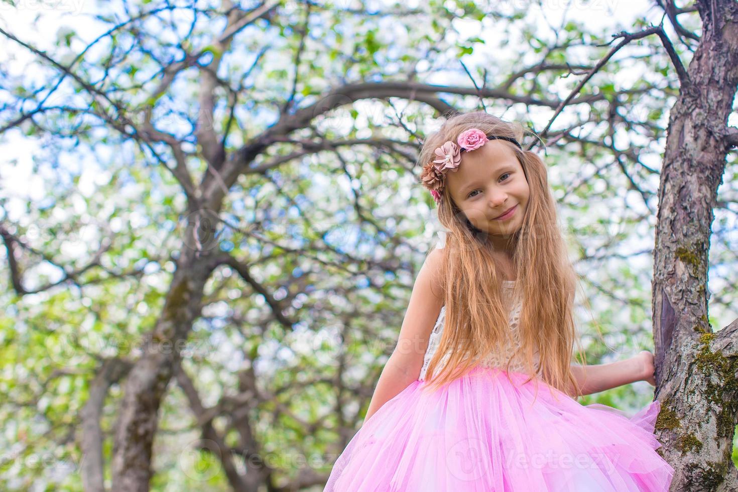 poco adorabile ragazza seduta su fioritura albero nel Mela giardino foto