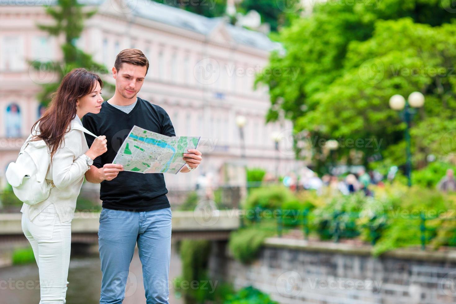 coppia in viaggio su loro luna di miele nel Europa. caucasico famiglia con città carta geografica nel ricerca di attrazioni foto