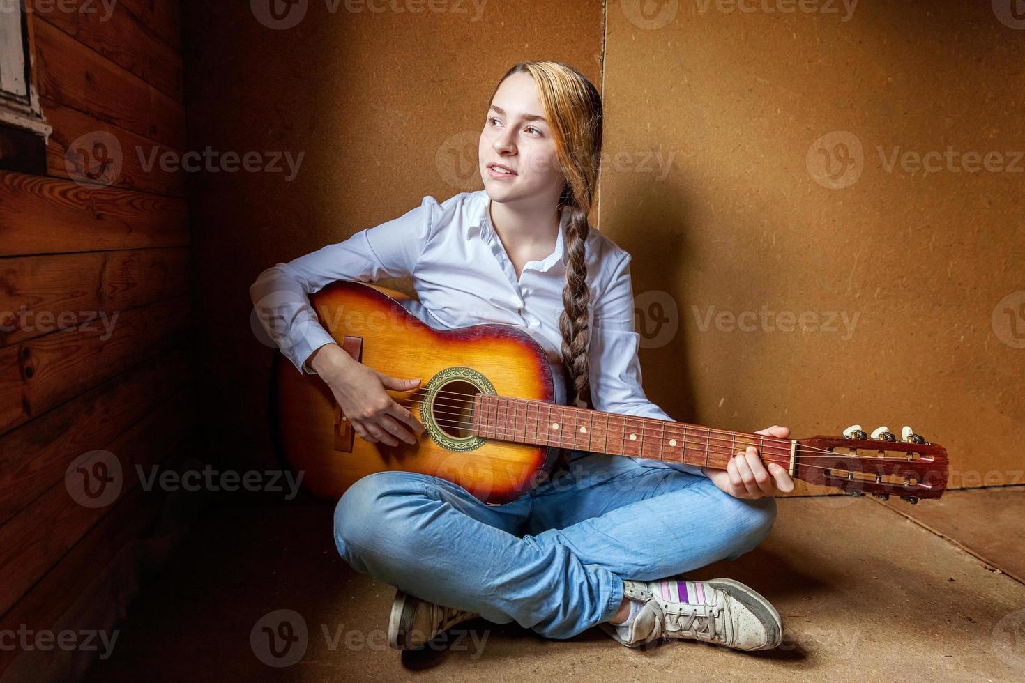 giovane fricchettone donna seduta su pavimento e giocando chitarra a casa. adolescente ragazza apprendimento per giocare canzone e scrittura musica nel sua camera. passatempo, stile di vita, relax, strumento, tempo libero, formazione scolastica concetto. foto