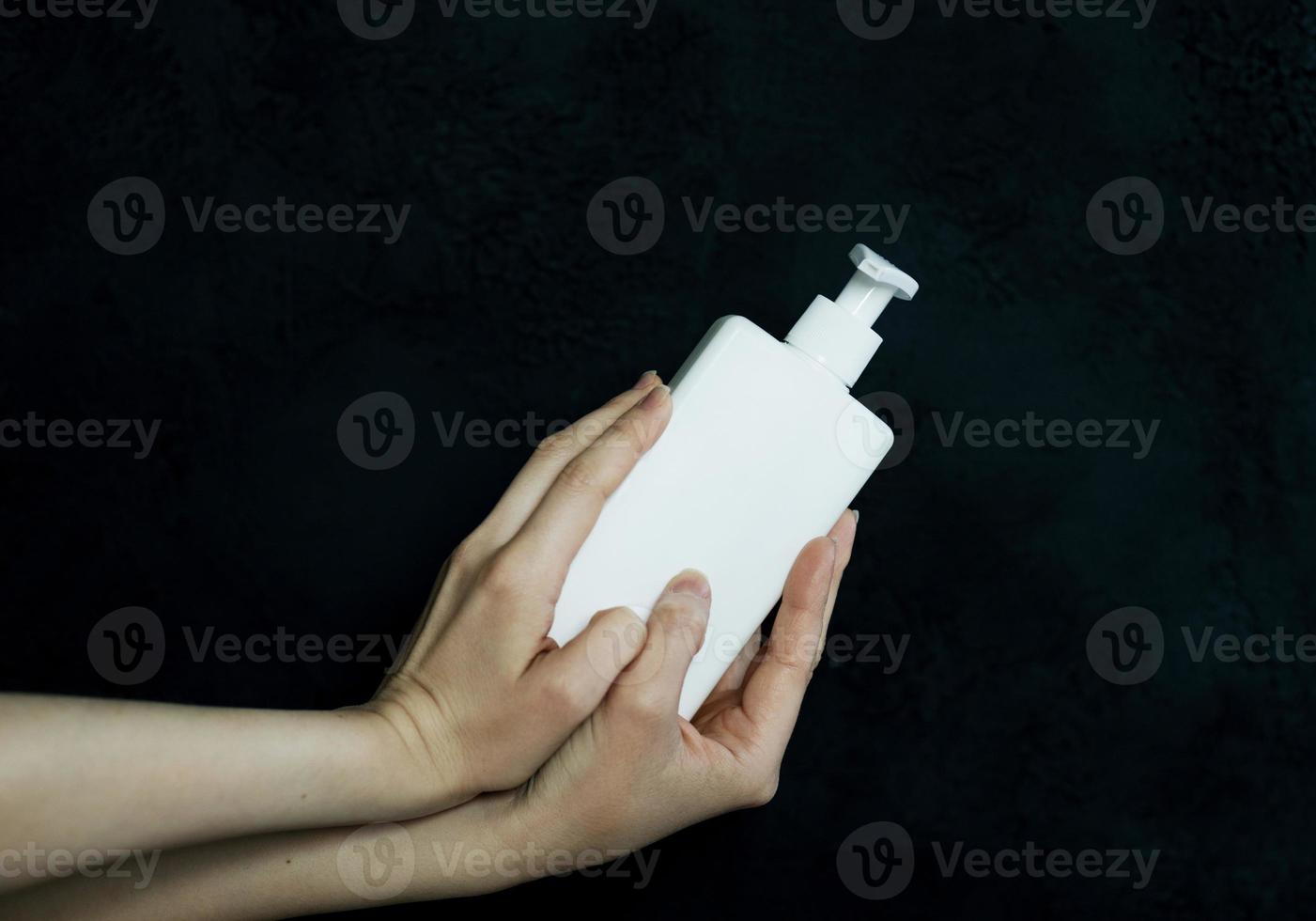 femmina mani Tenere bianca lozione bottiglia foto
