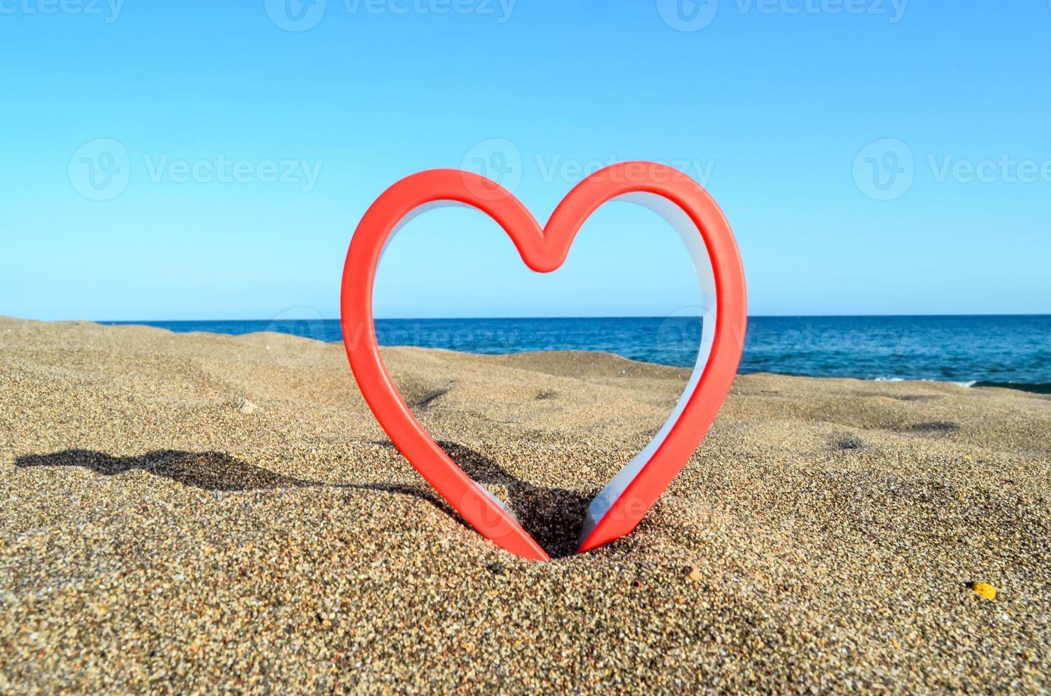 rosso plastica cuore su il spiaggia foto