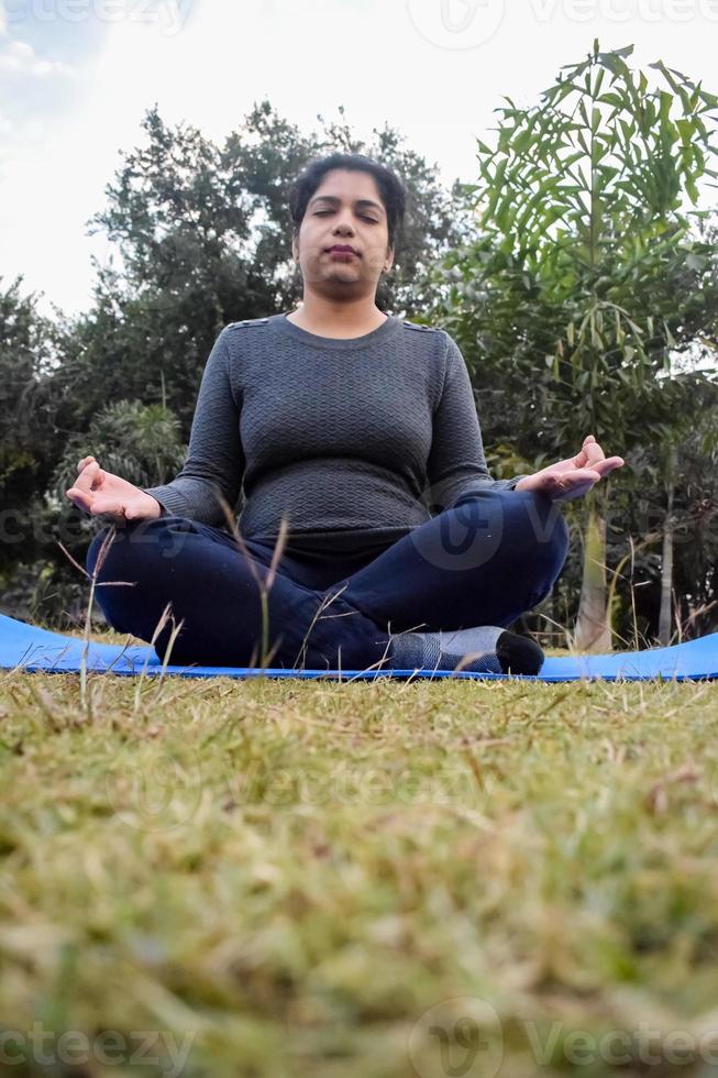 giovane indiano donna praticante yoga all'aperto nel un' parco. bellissimo ragazza pratica di base yoga posa. quiete e relax, femmina felicità. di base yoga pose all'aperto foto