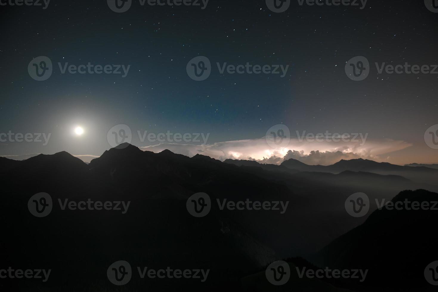 nel il notte, fulmine iin il inferiore valle, con un' stellato cielo e il Luna. foto