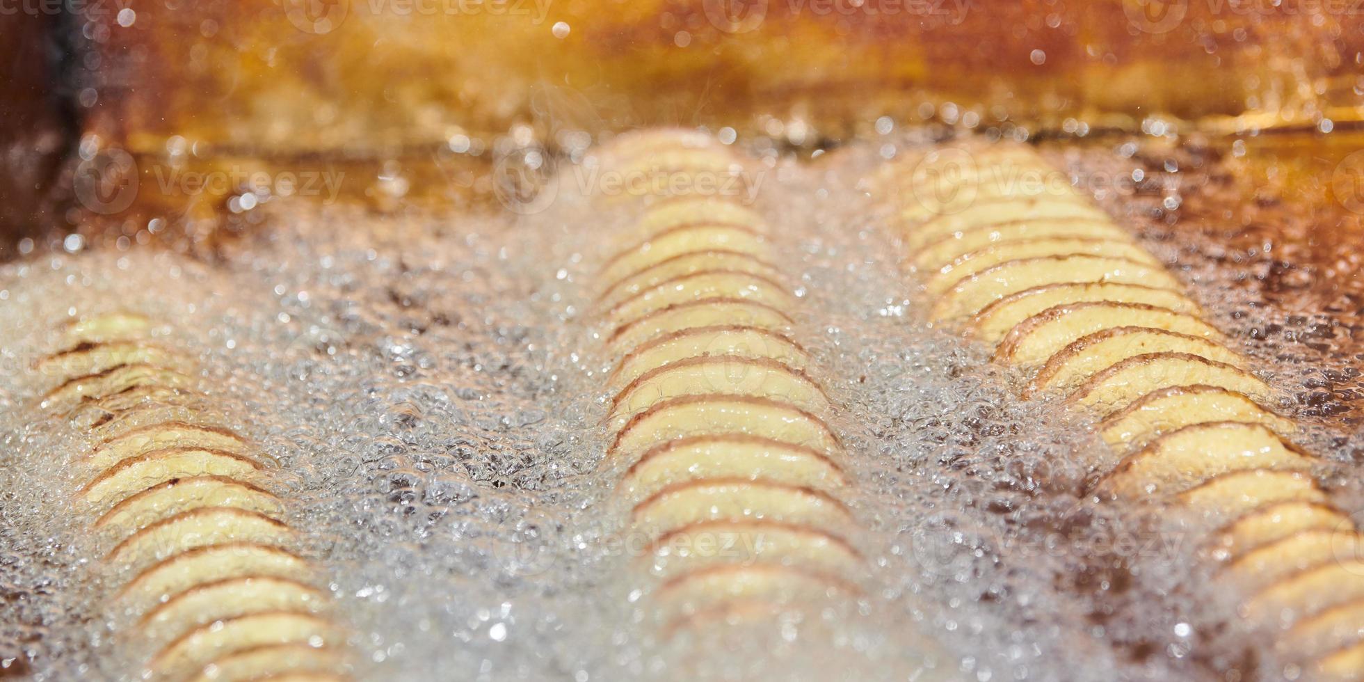 cucinando spirale fritte Patata nel bollente olio, ricco nel Grasso e calorie veloce cibo, malsano delizioso foto