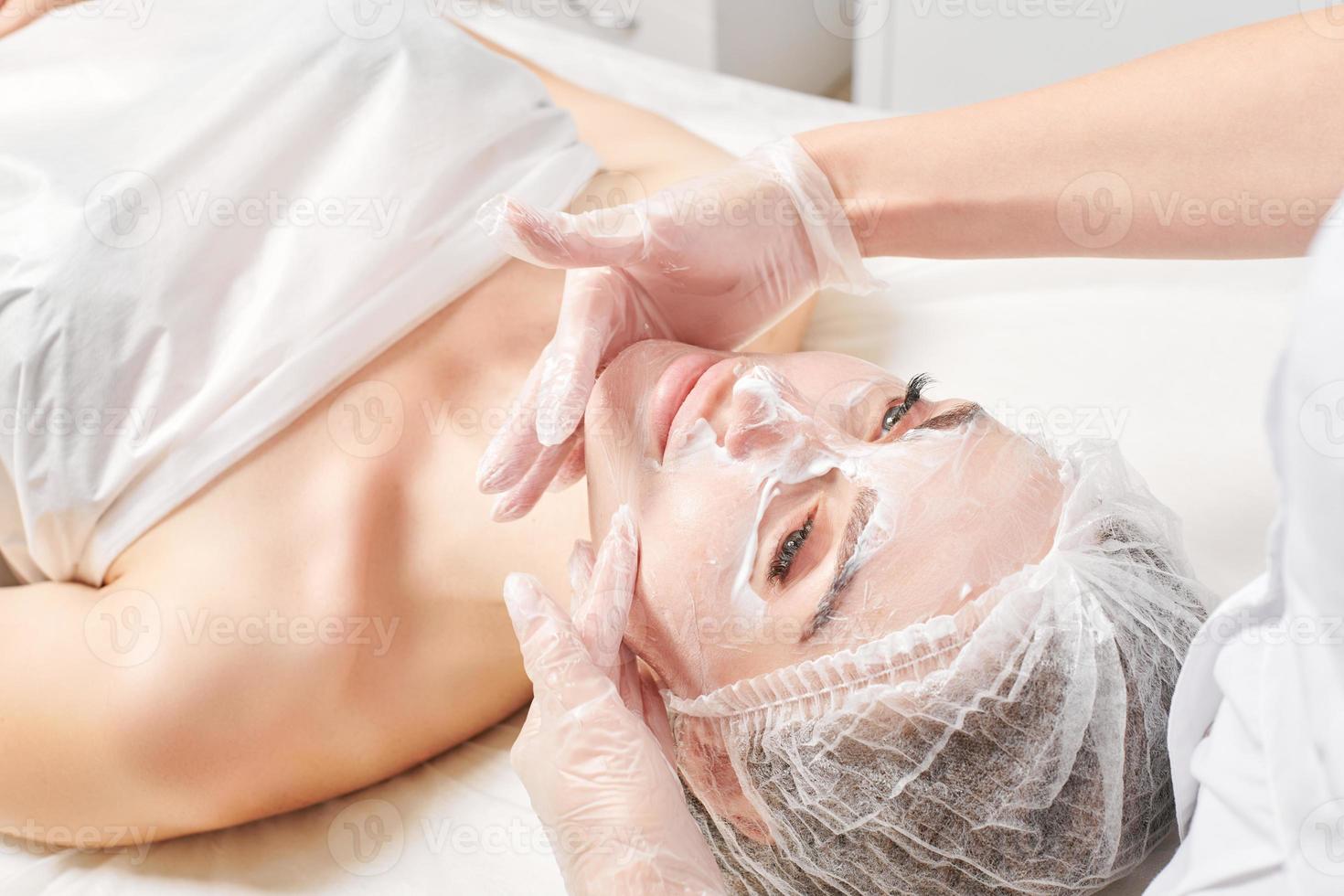 cosmetologo massaggi crema maschera in donna viso pelle per ringiovanimento, procedura nel bellezza salone foto