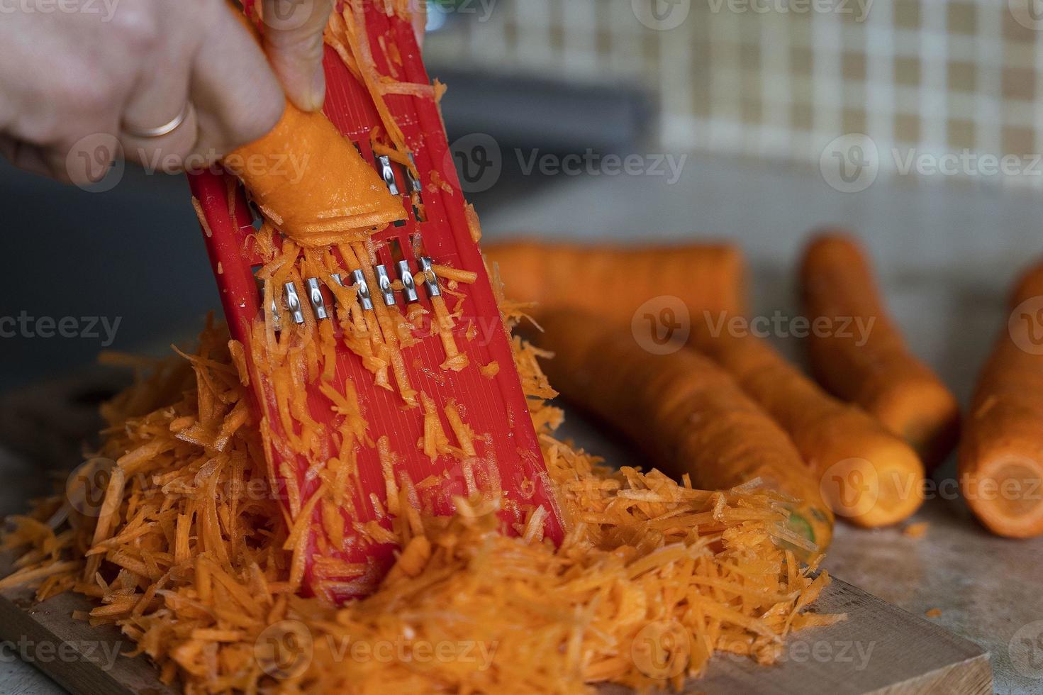 della padrona di casa mani grattugiare carote su un' grattugia per coreano carote, stile di vita, cucinando , salutare mangiare foto