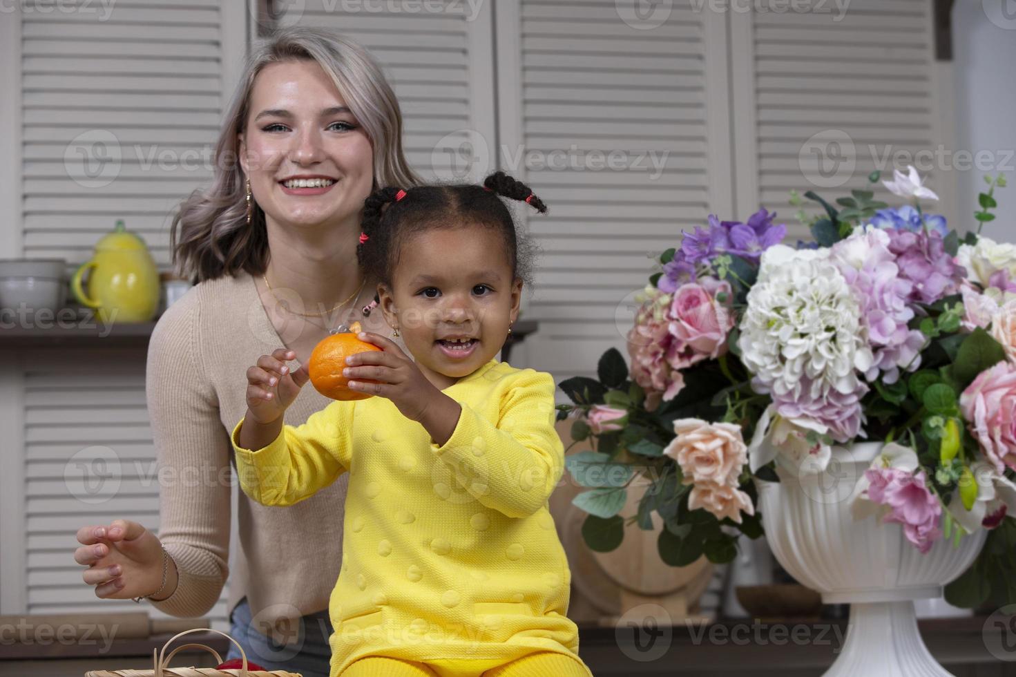 multietnico mamma e figlia giocare a casa nel il cucina. allegro madre con poco figlia di africano nazionalità. famiglia a partire dal diverso gare. foto