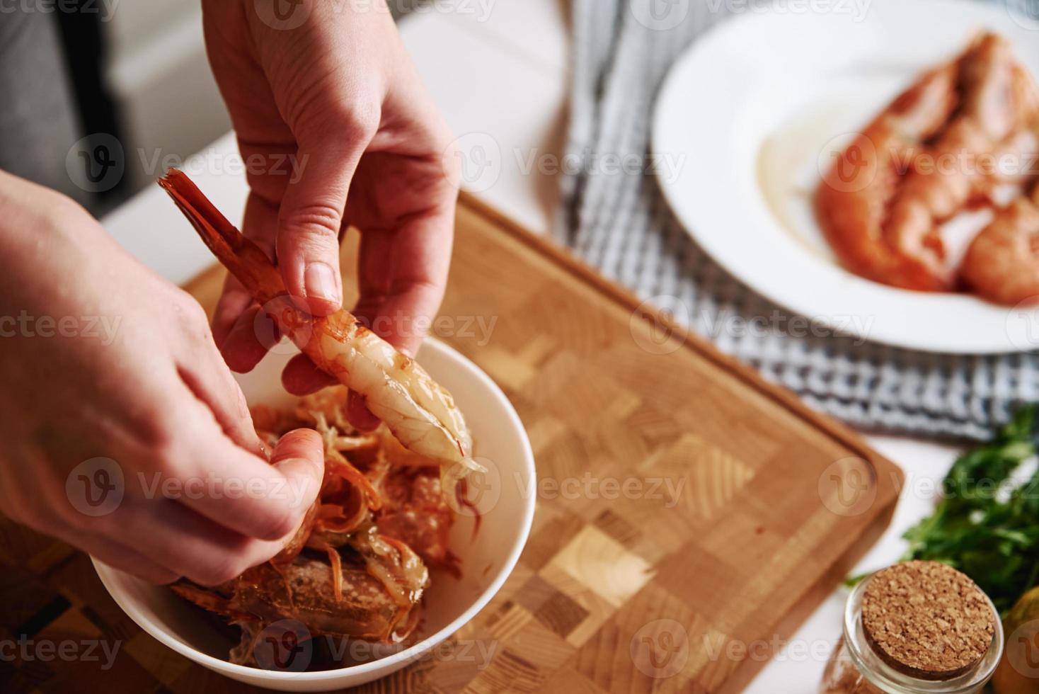 donna pulizia gamberetti per cucinando. processi di mani sbucciare gamberetti conchiglia foto