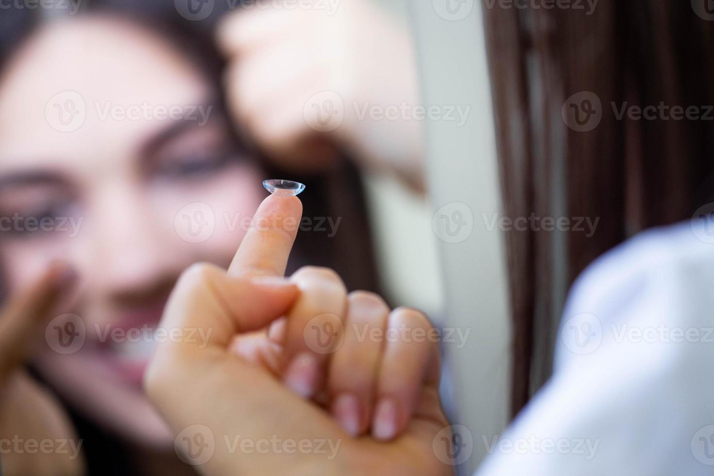 giovane donna mettendo contatto lente nel sua giusto occhio, vicino su foto