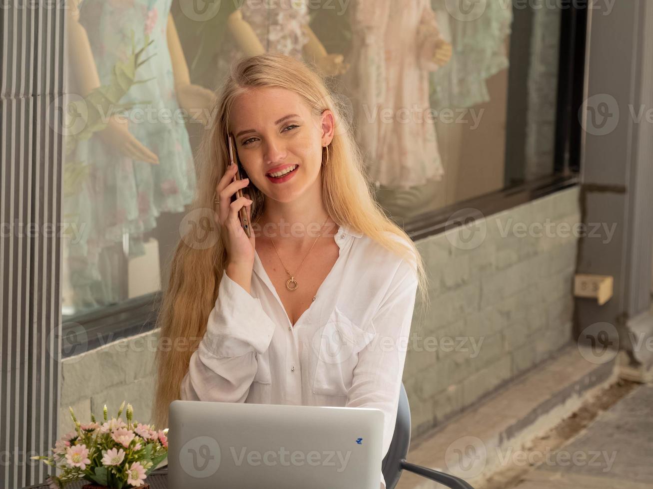 donna d'affari bianca camicia persona Guarda a telecamera contento Sorridi parlare parlare telefono smartphone tavoletta comunicazione tecnologia digitale femmina bellissimo giovane adulto attività commerciale copia spazio sfondo concetto foto