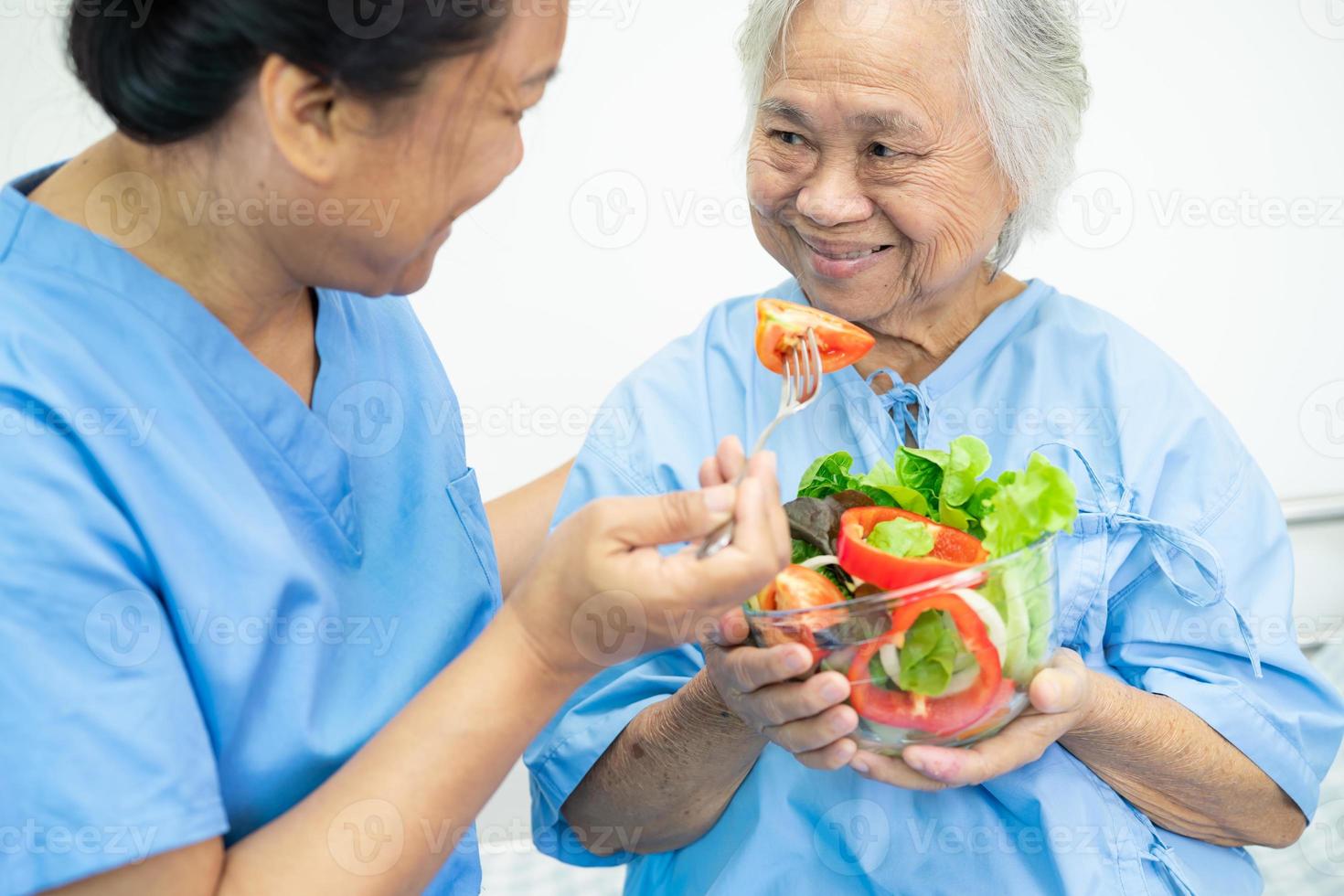 asiatico anziano o anziana signora anziana paziente che mangia colazione vegetale cibo sano con speranza e felice mentre è seduto e affamato sul letto in ospedale. foto