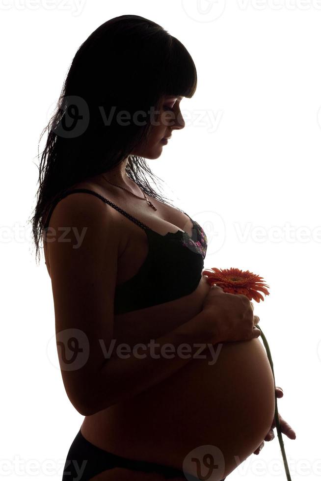 incinta giovane brunetta con fiore. isolato foto