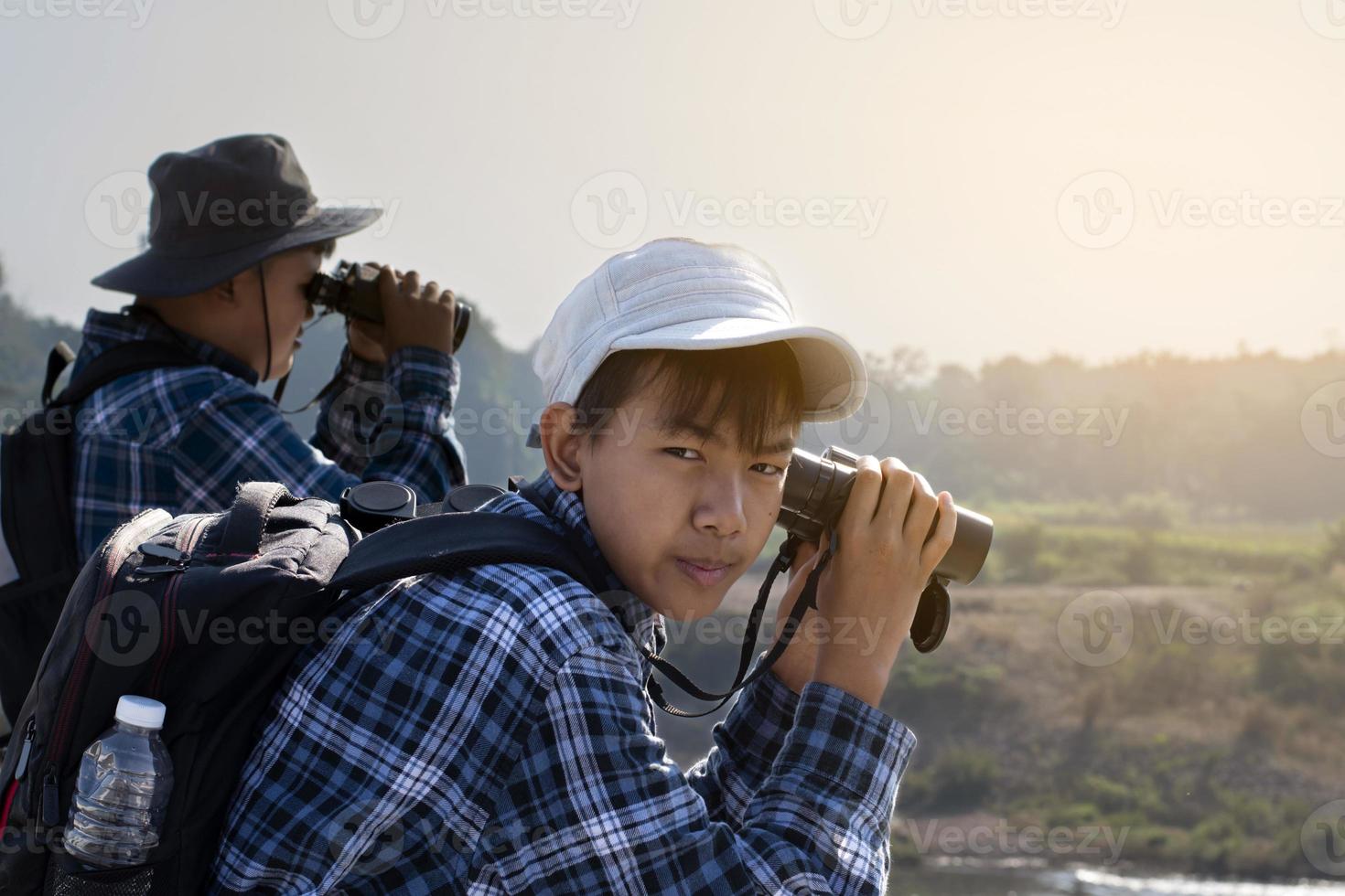 asiatico ragazzi siamo utilizzando binocolo per orologio uccelli e pesce nel Locale nazionale parco durante estate campo, idea per apprendimento creature e natura animali e insetti al di fuori il aula. foto