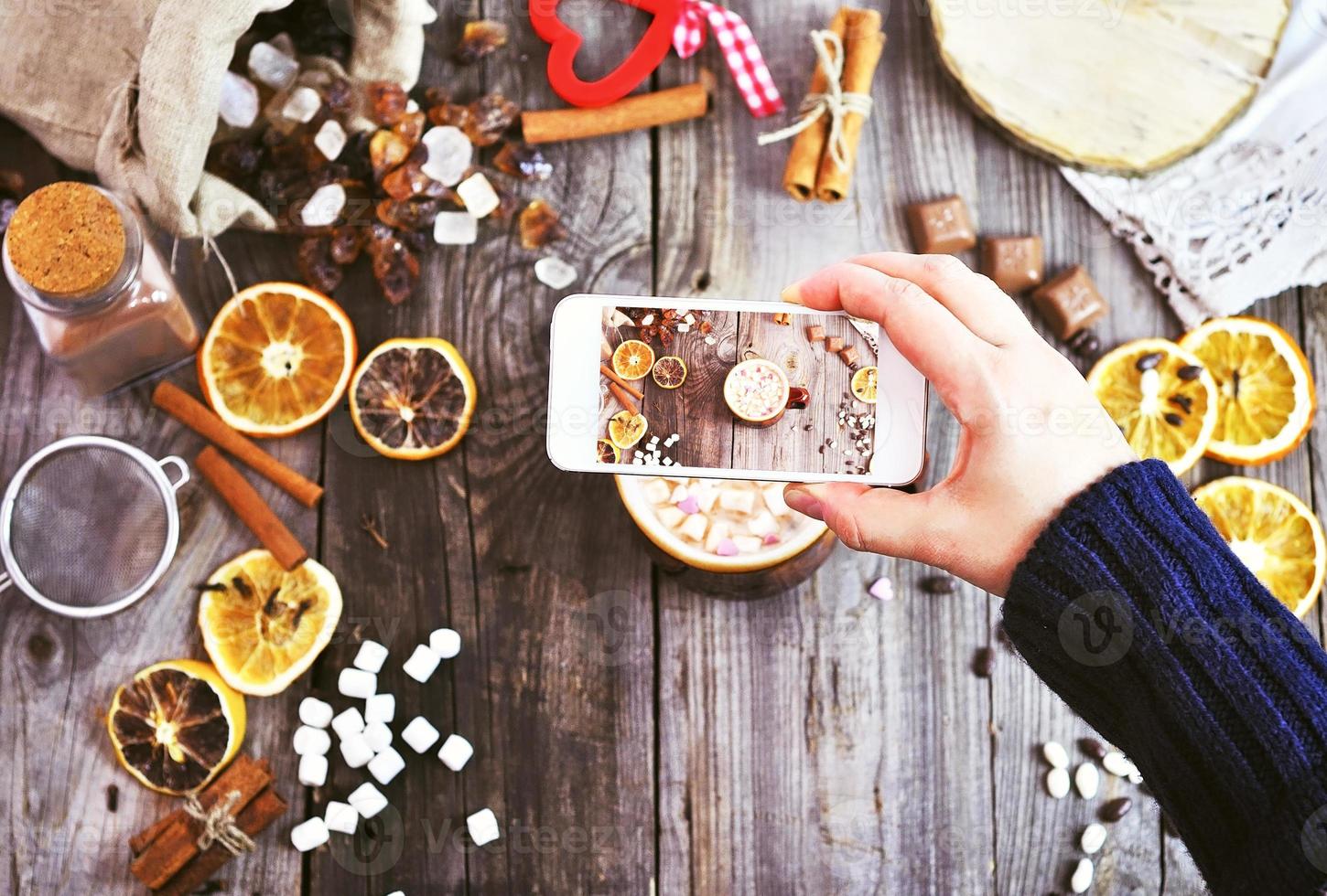 un' bianca smartphone nel un' donna di mano prende un' fotografia di un' boccale con un' bevanda e pezzi di marshmallow foto