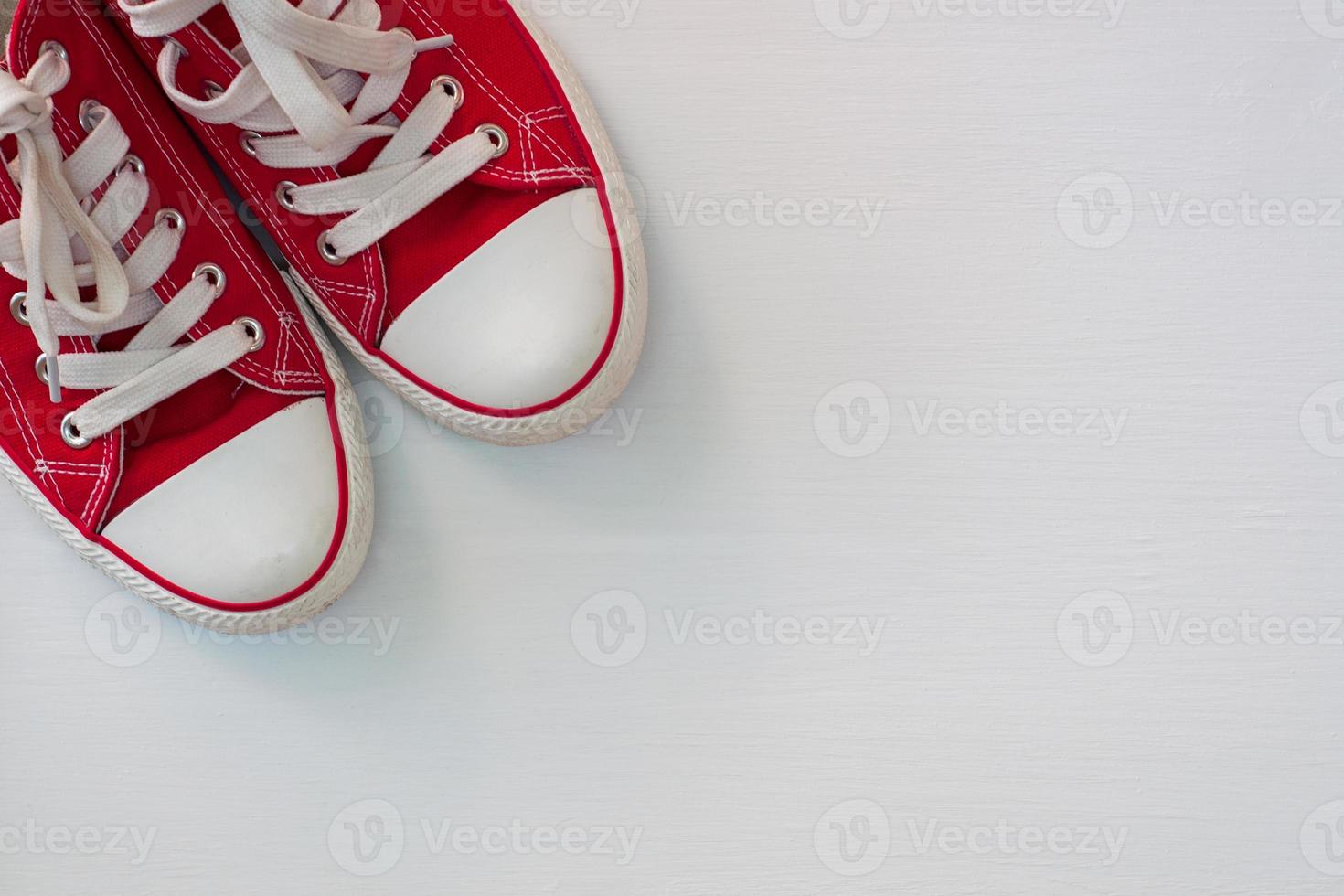 paio di rosso scarpe da ginnastica gioventù su un' bianca di legno superficie foto