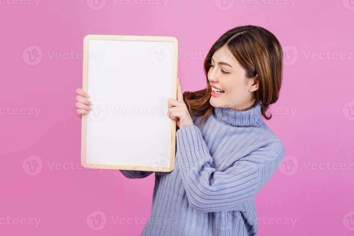 ritratto di contento giovane donna Tenere un vuoto bianca cartellone al di sopra di isolato rosa sfondo. foto