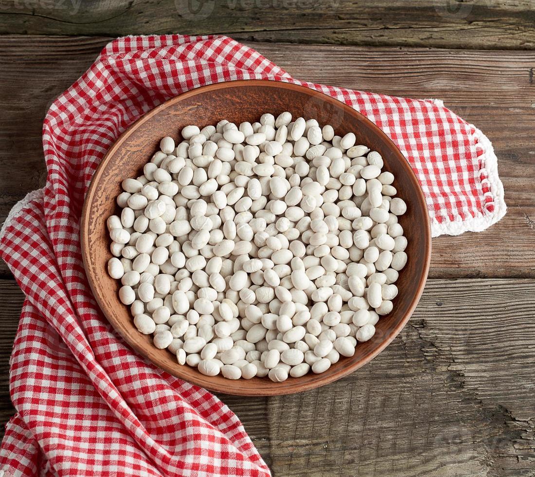 crudo il giro bianca fagioli nel un' piatto su un' di legno tavolo foto