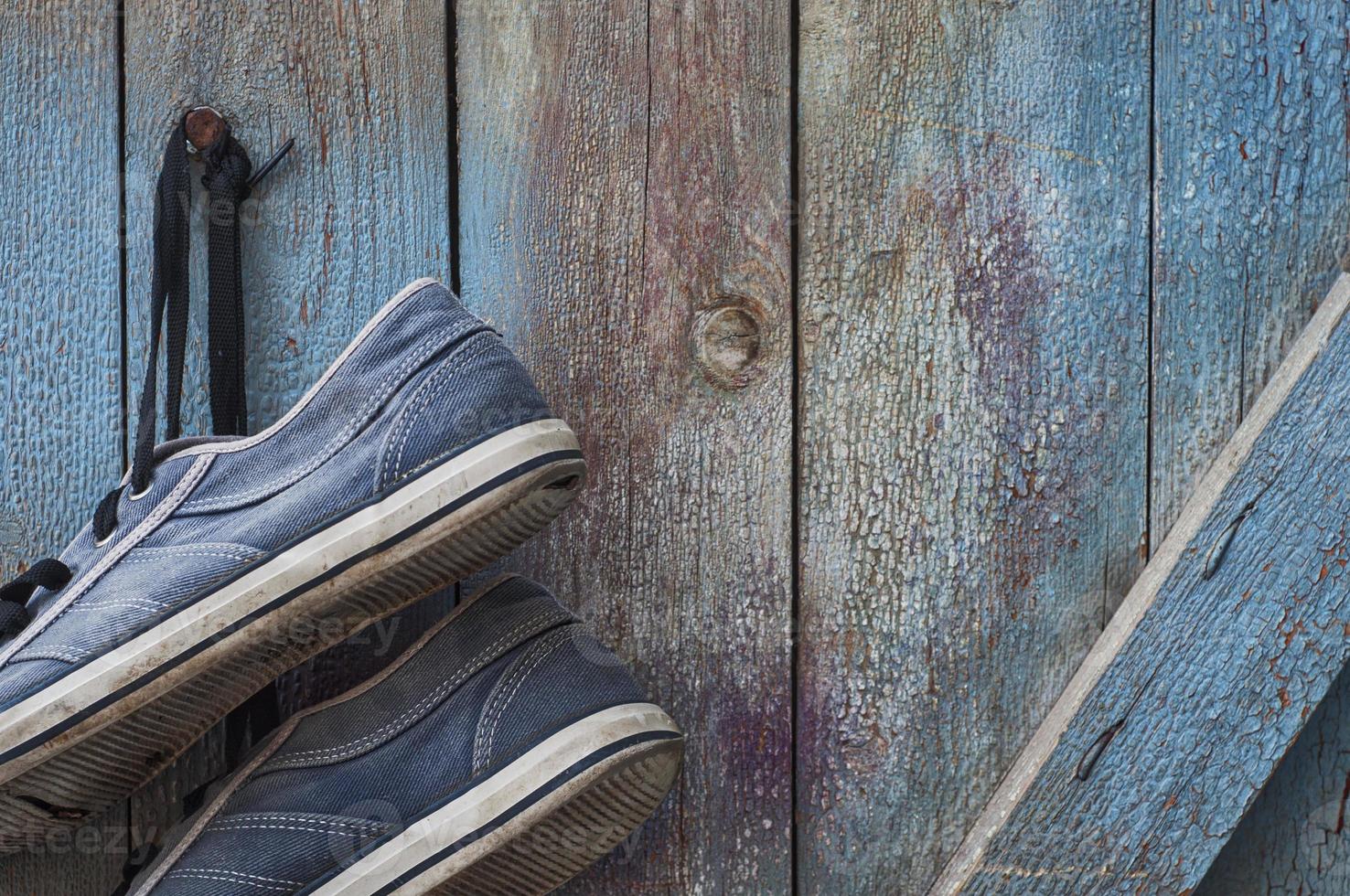 paio di vecchio sporco e logoro blu scarpe da ginnastica appendere su un' chiodo foto