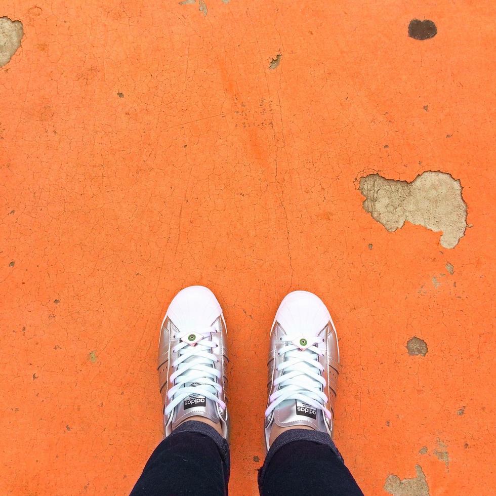 persona che indossa scarpe da ginnastica in piedi sul pavimento arancione foto