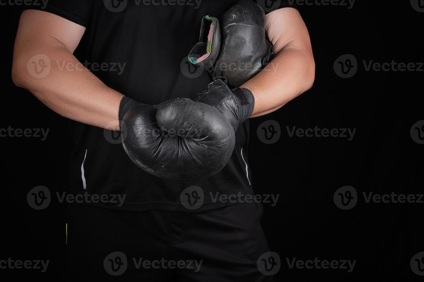 adulto muscolare uomo nel nero Abiti mette su pelle nero boxe guanti foto